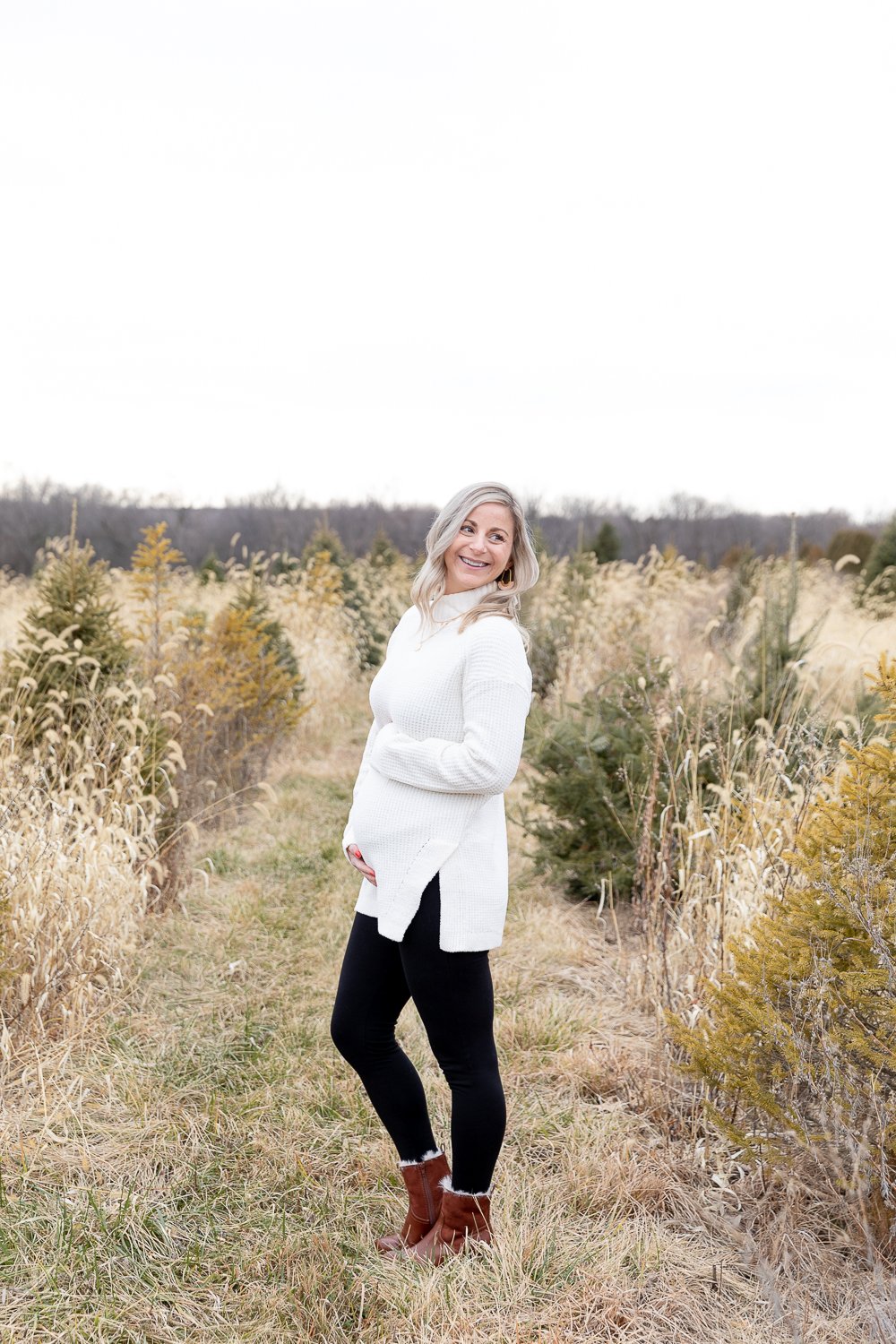 mother holding her pregnant belly at a tree farm