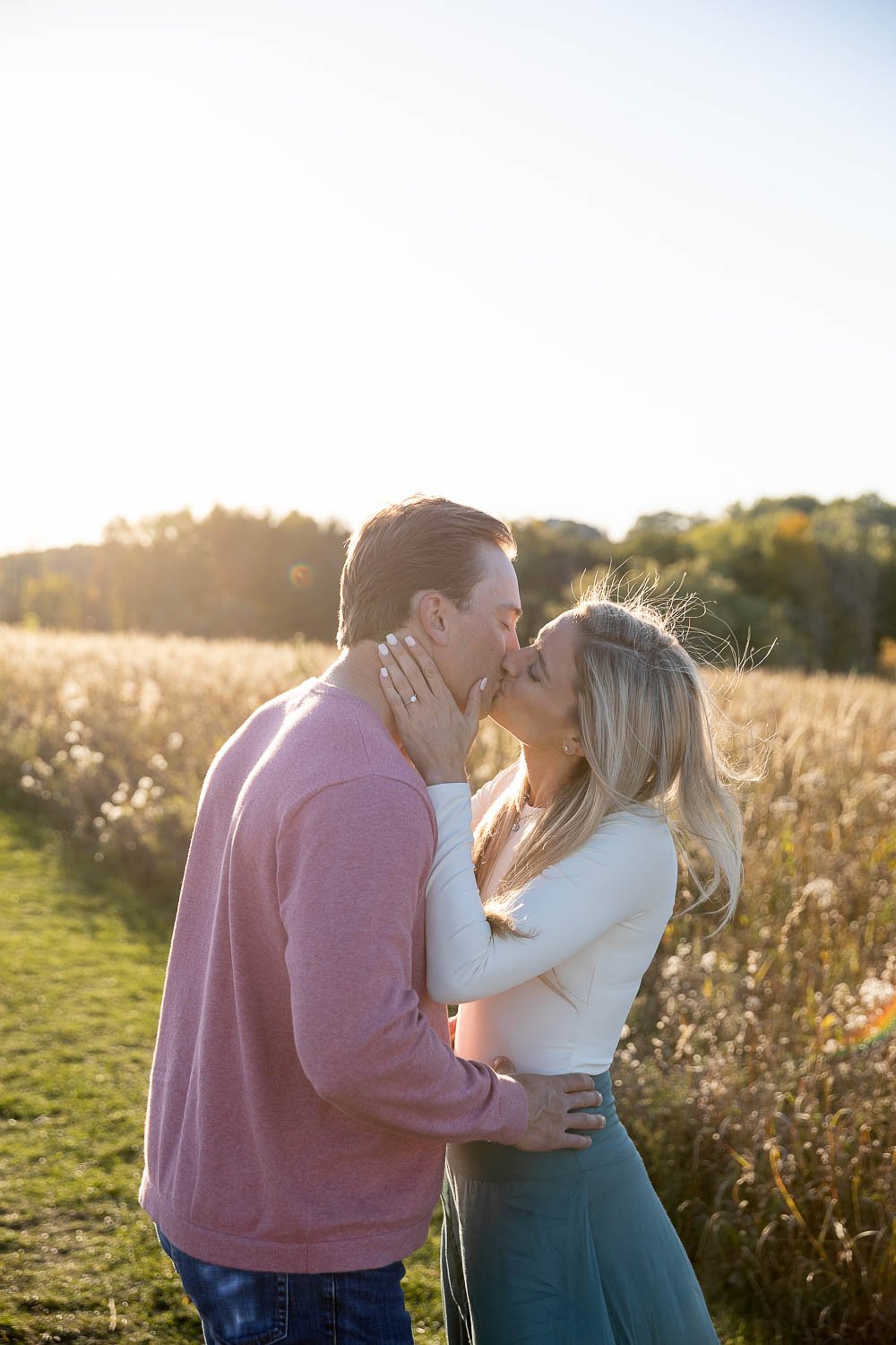 engaged couple kissing in the field at Retzer Nature center