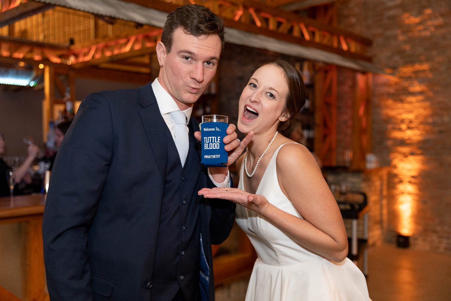 bride and groom posing with custom can coozie favor at Factory on barclay