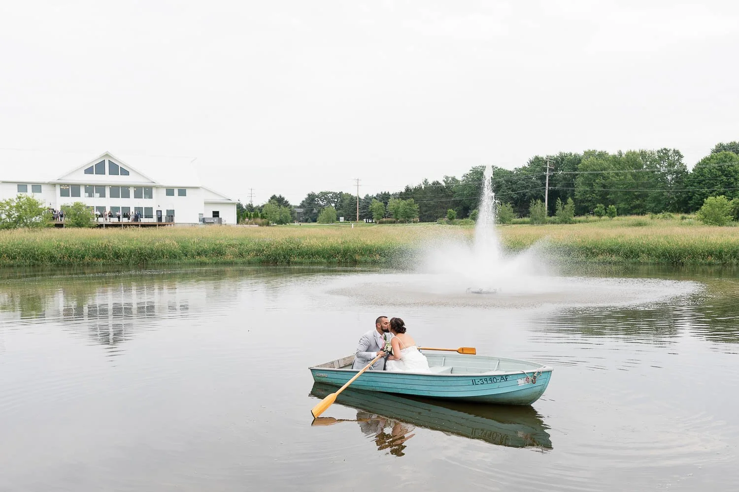 bride and groom in row boat and kissing while floating on the water