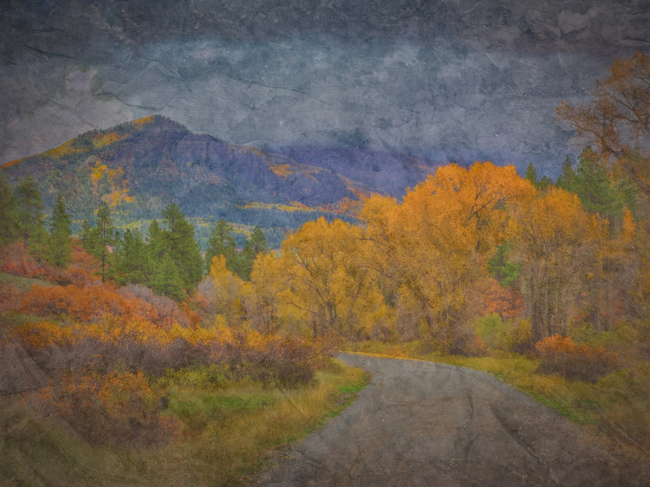 A landscape photograph of mountains and trees in autumn colors under a cloudy sky.