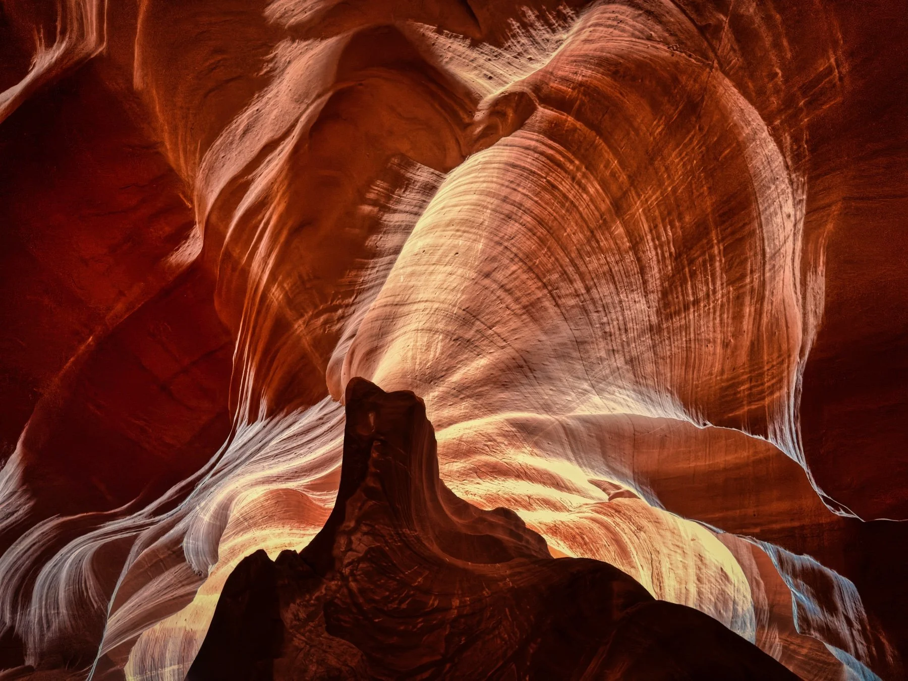 Inside a slot canyon with smooth, flowing sandstone walls illuminated by soft light, creating a warm glow with shades of orange and red.
