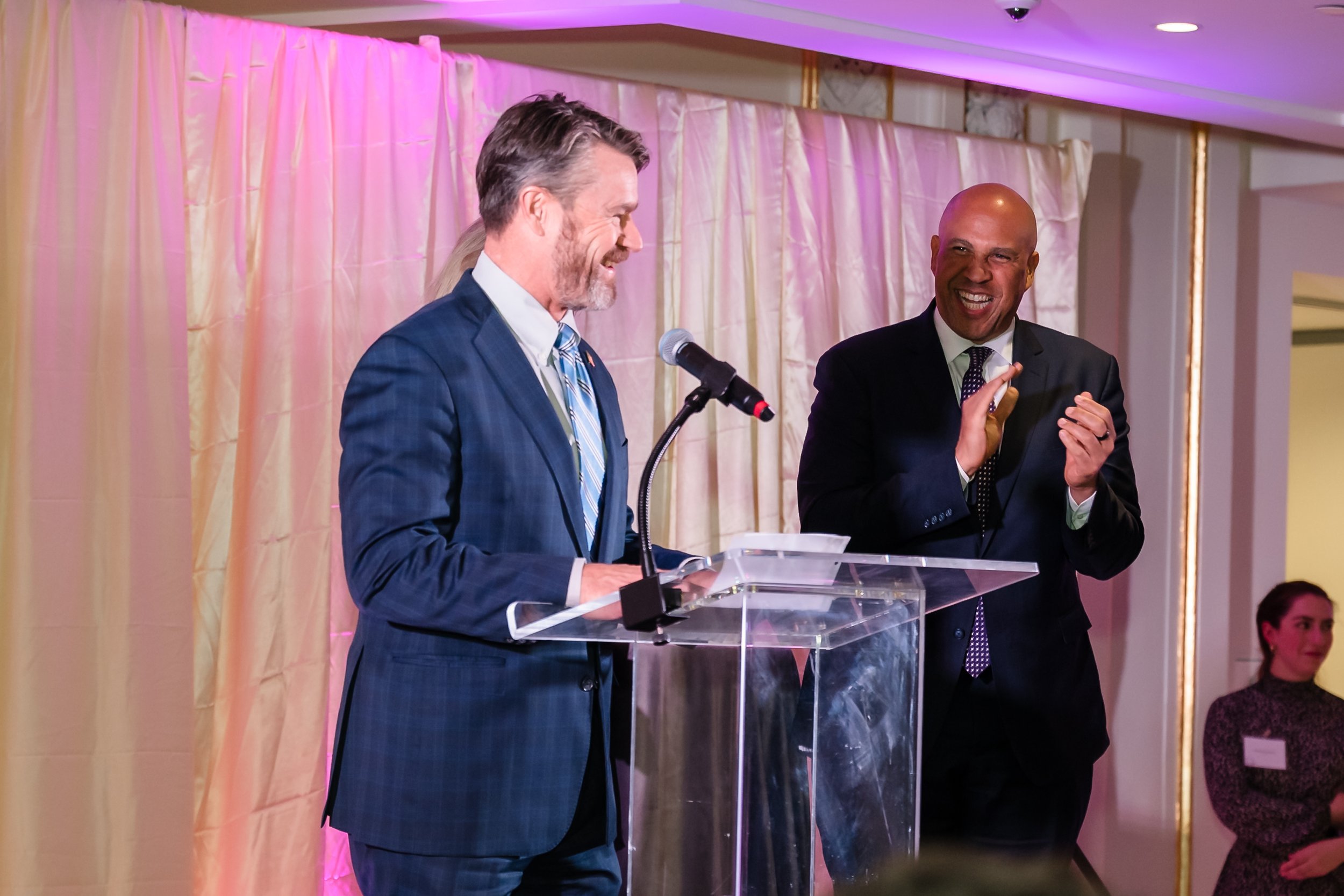 2025 Senate Statesmanship Honorees Todd Young (R-IN, speaking) and Cory Booker (D-NJ, right) on stage to give remarks