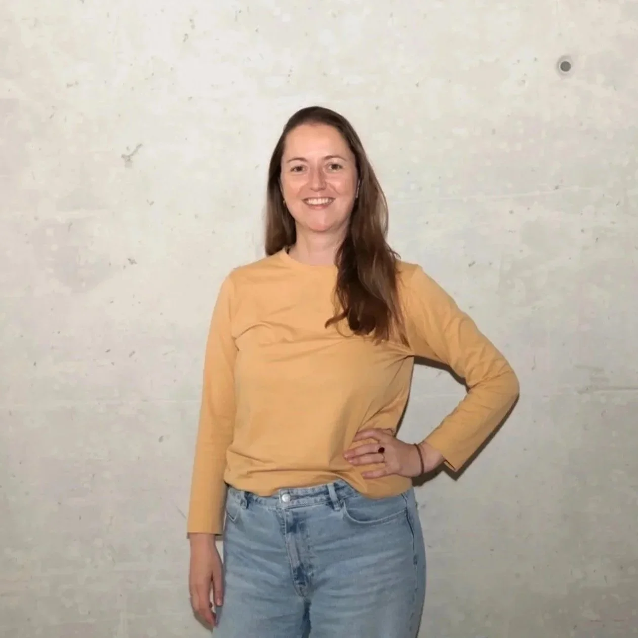Black-and-white photo of a smiling woman with long hair outdoors, with hills in the background.