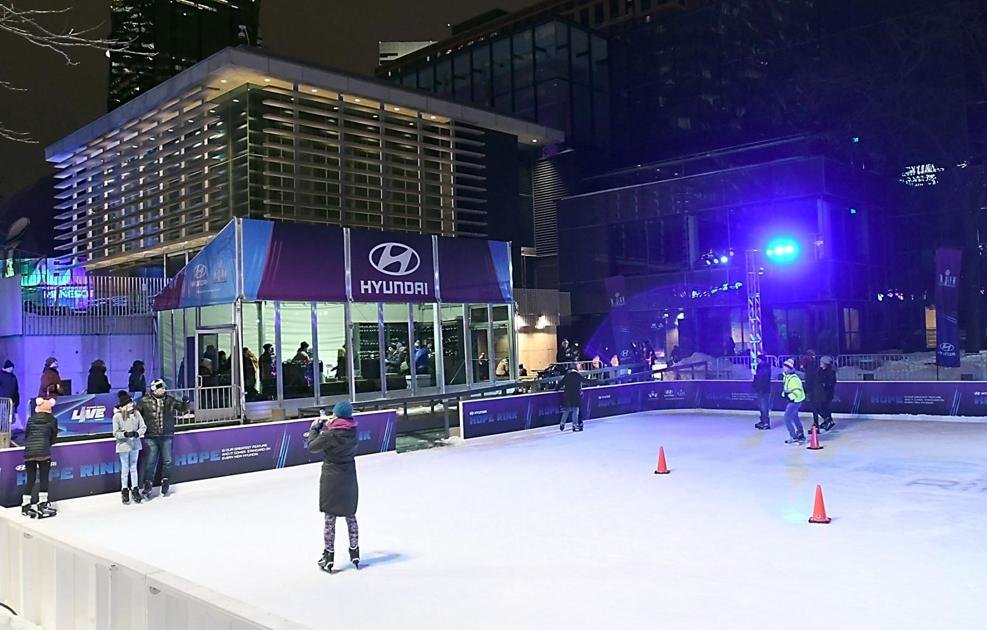 Outdoor ice skating rink with a Hyundai-branded building and skaters enjoying the activity at night.