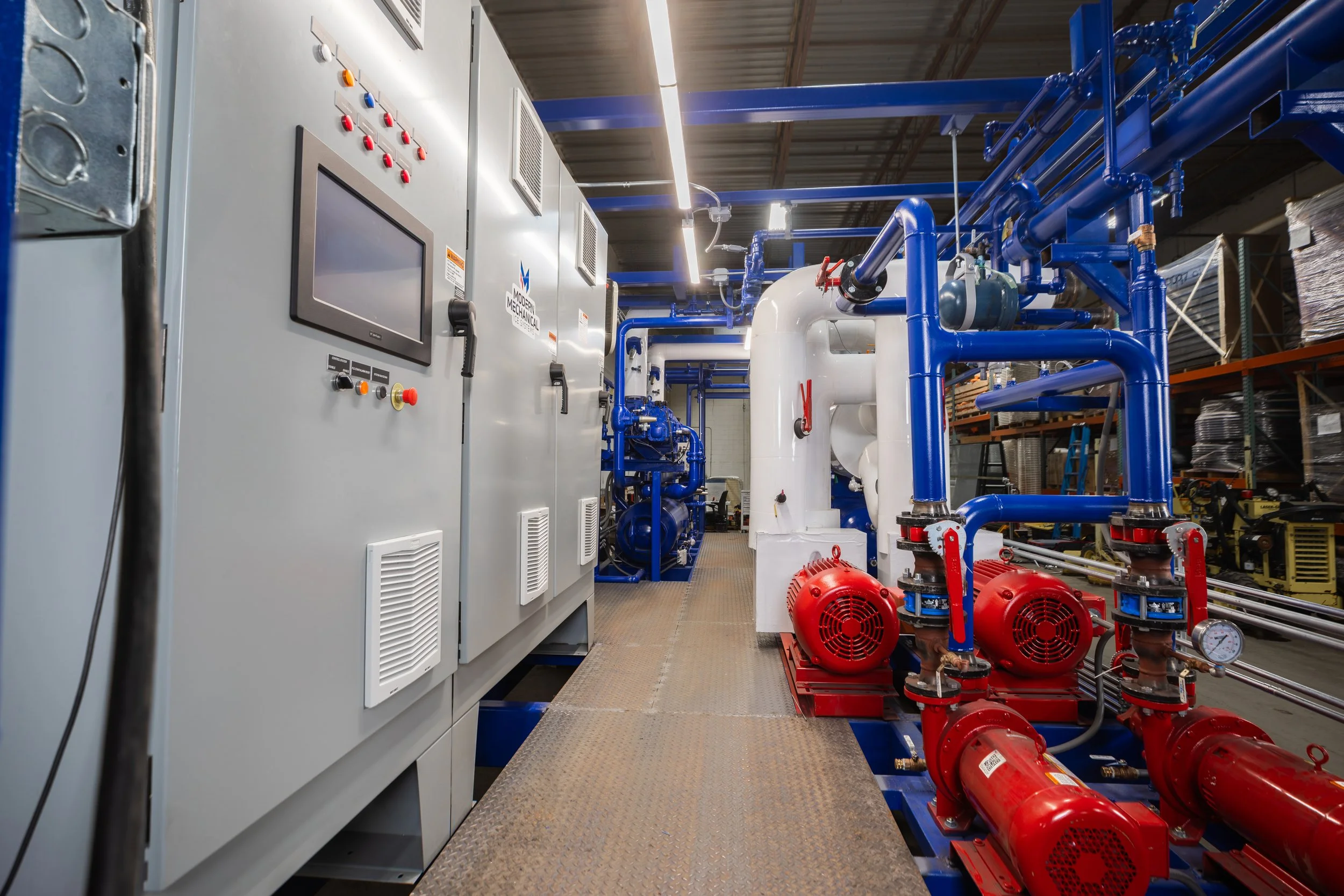 Industrial refrigeration equipment with pipes, tanks, gauges, and a logo for Modern Mechanical Ice Systems.