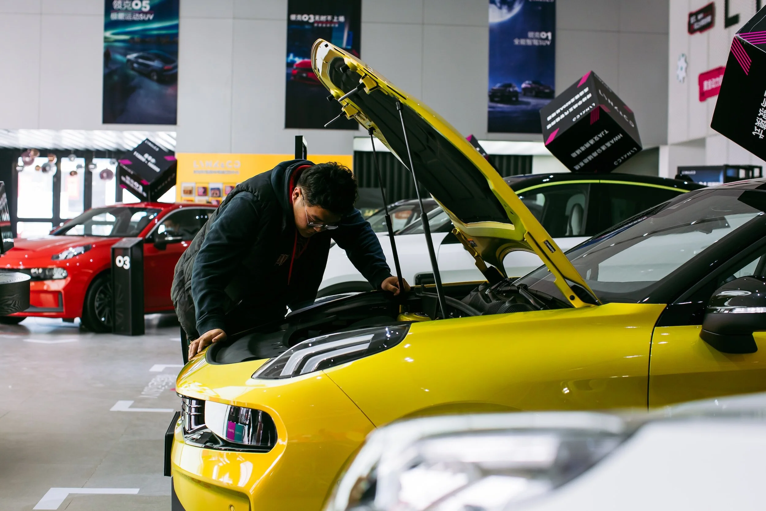 Man looking into the hood of a yellow chrevrolet camaro