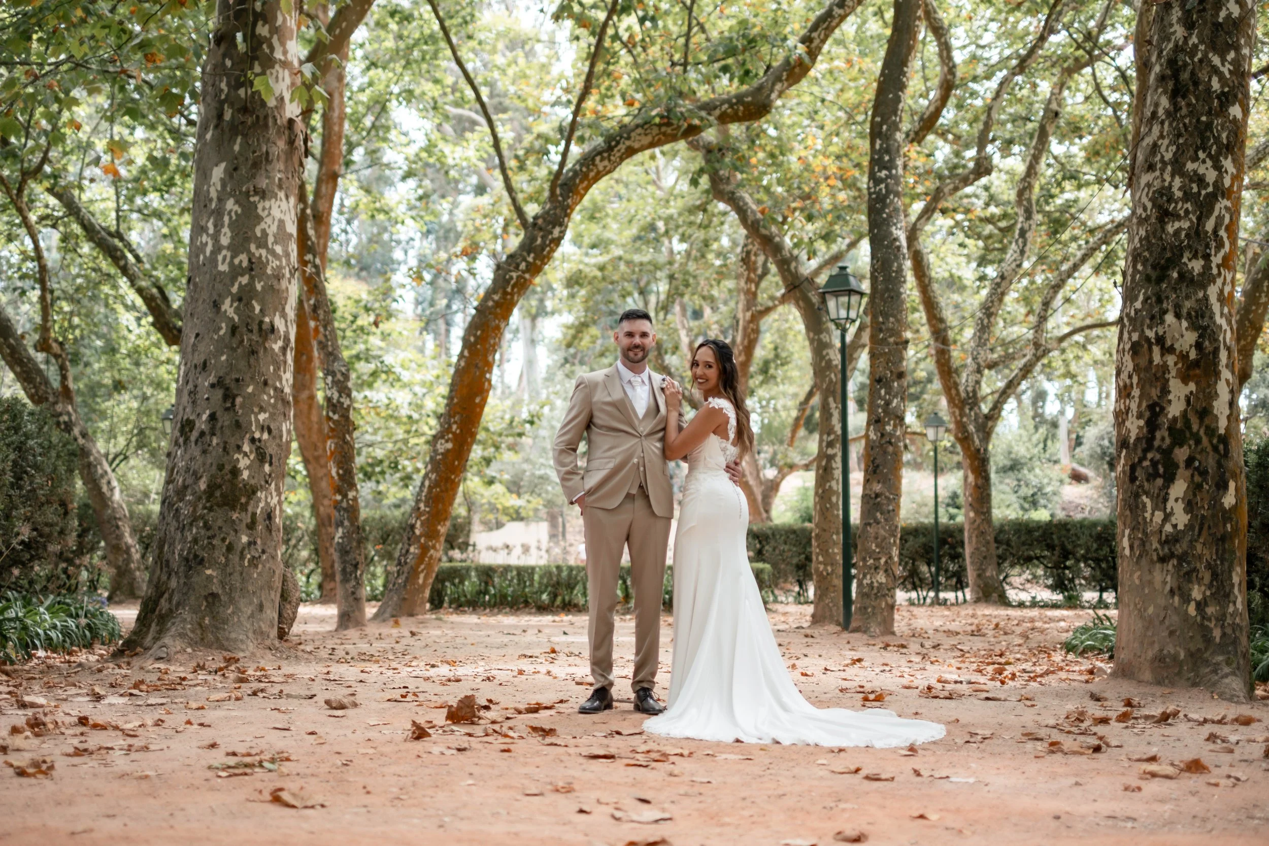 Noivos em retrato de corpo inteiro entre árvores durante sessão de casamento