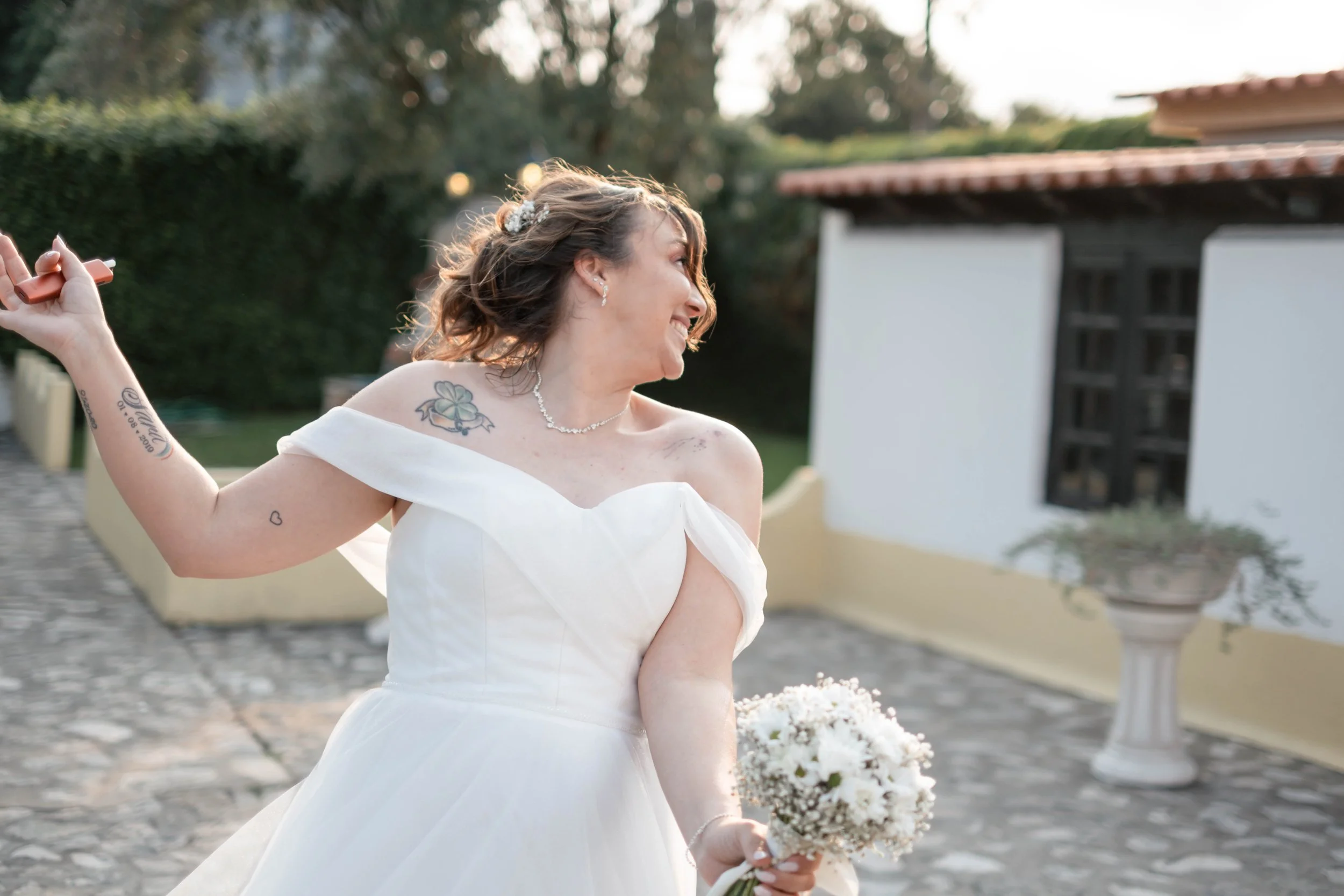 Noiva a sorrir ao ar livre com bouquet durante o dia do casamento