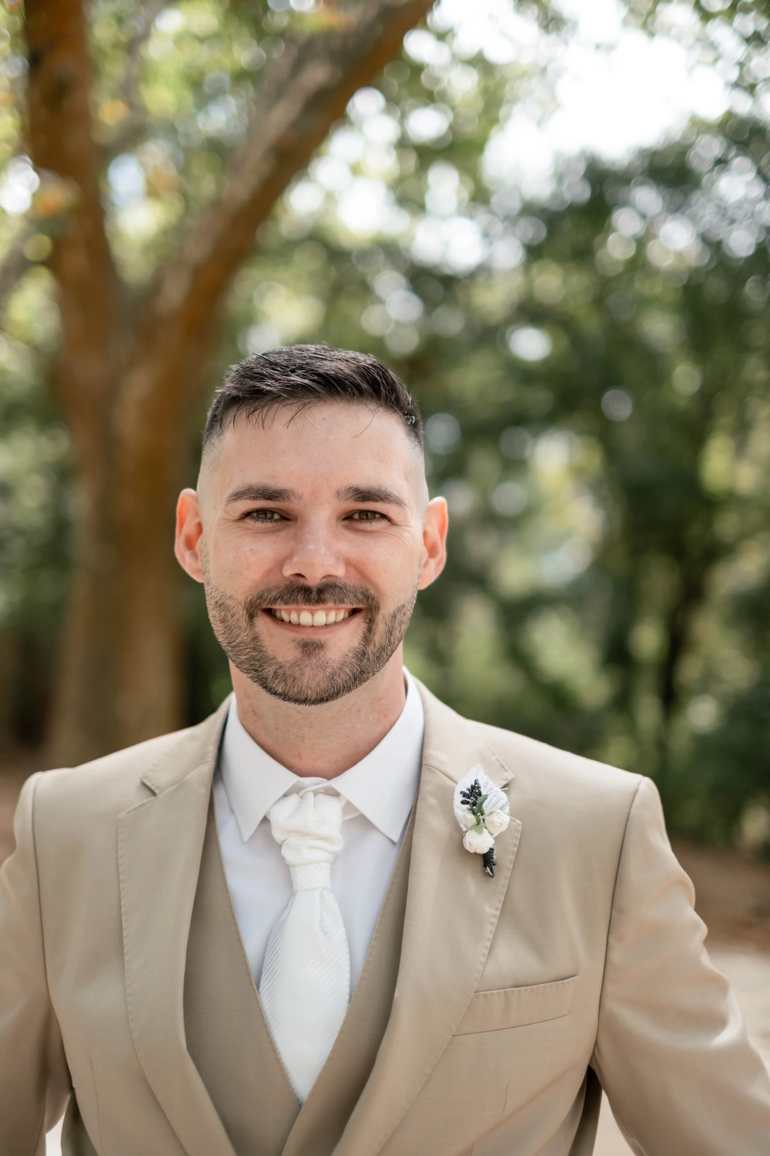 Retrato próximo do noivo com boutonnière branca no fato