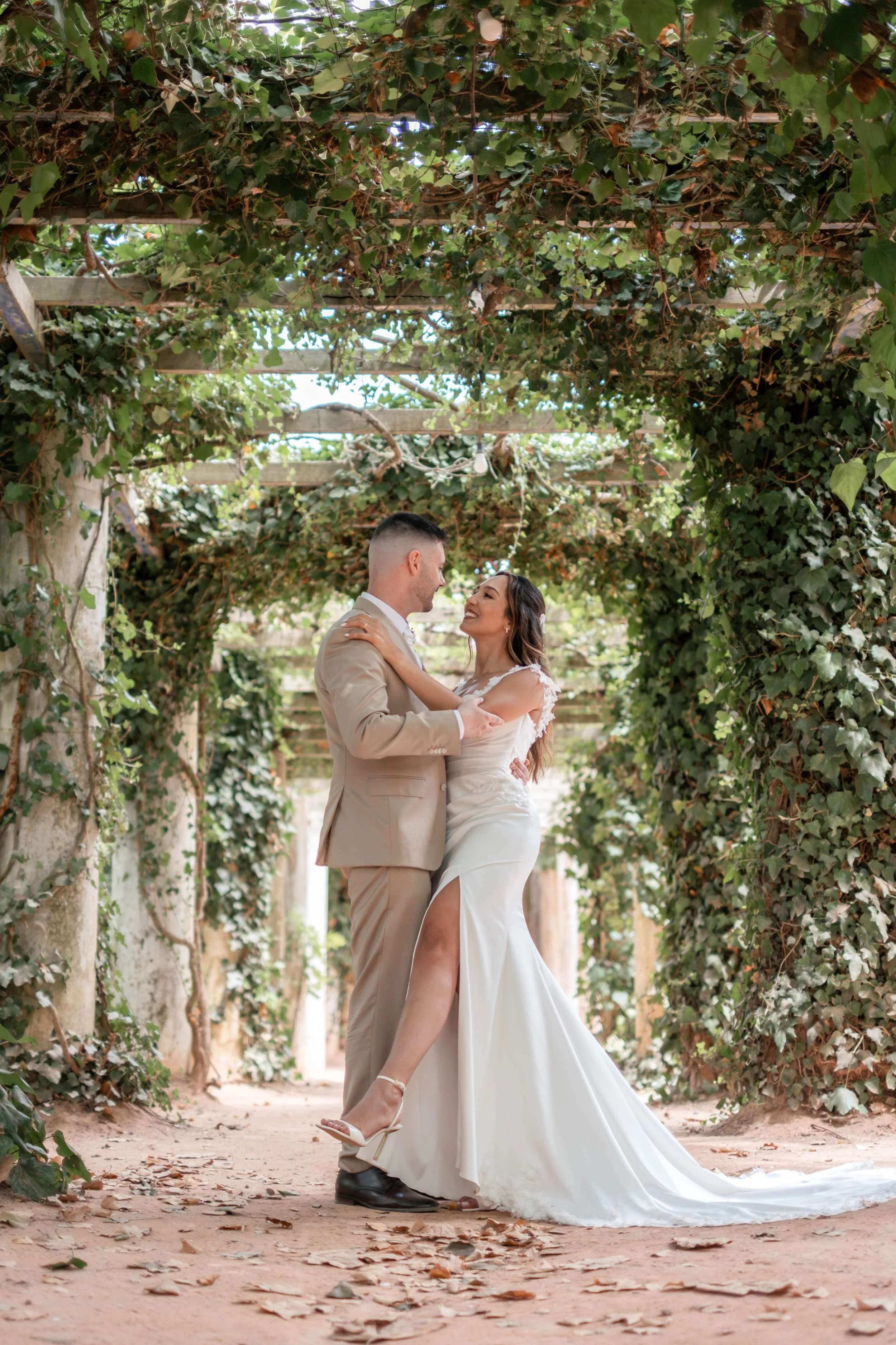 Noivos a beijarem-se sob uma pérgola durante sessão de casamento