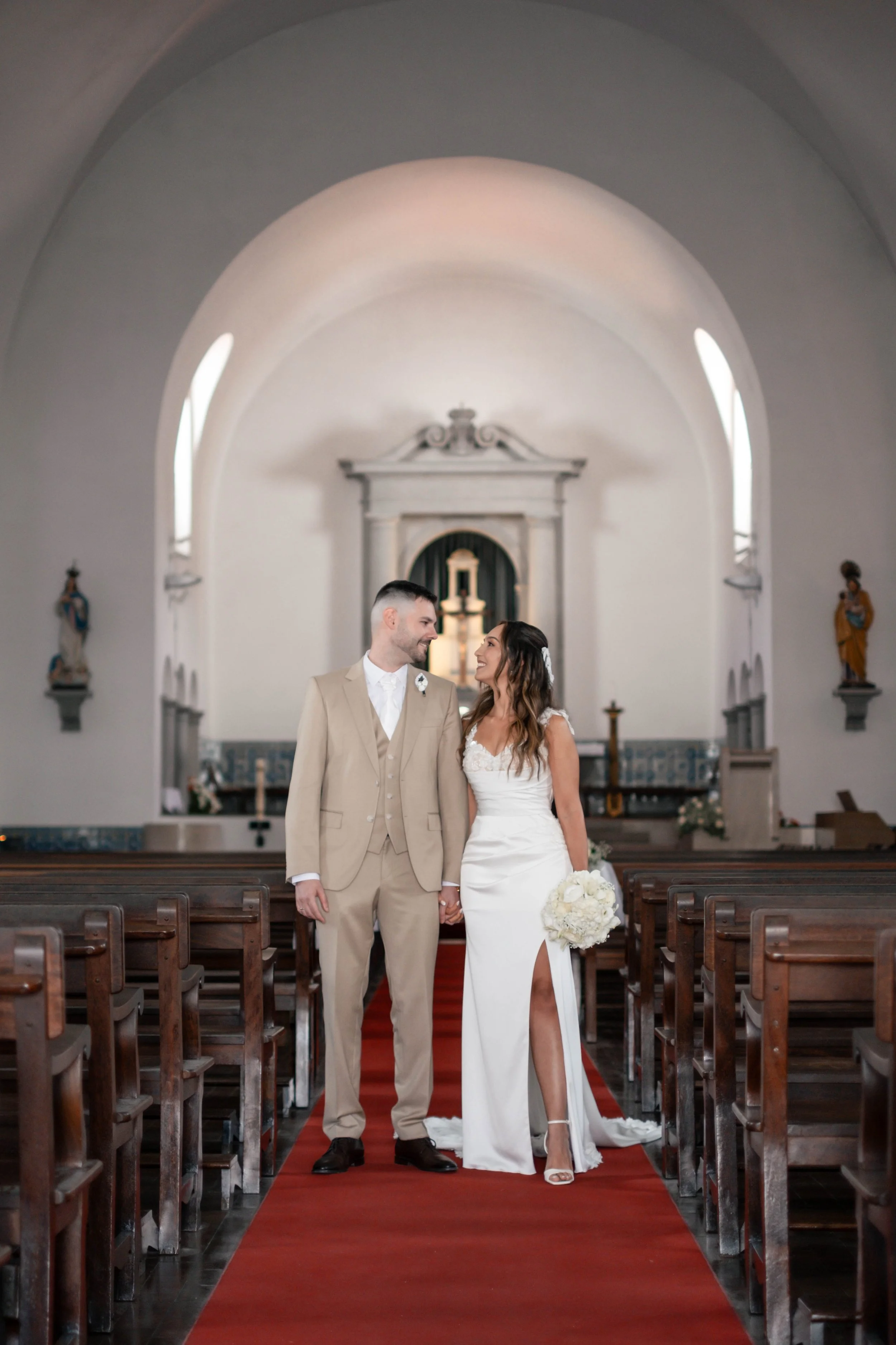 Noivos em retrato no corredor central da igreja após a cerimónia