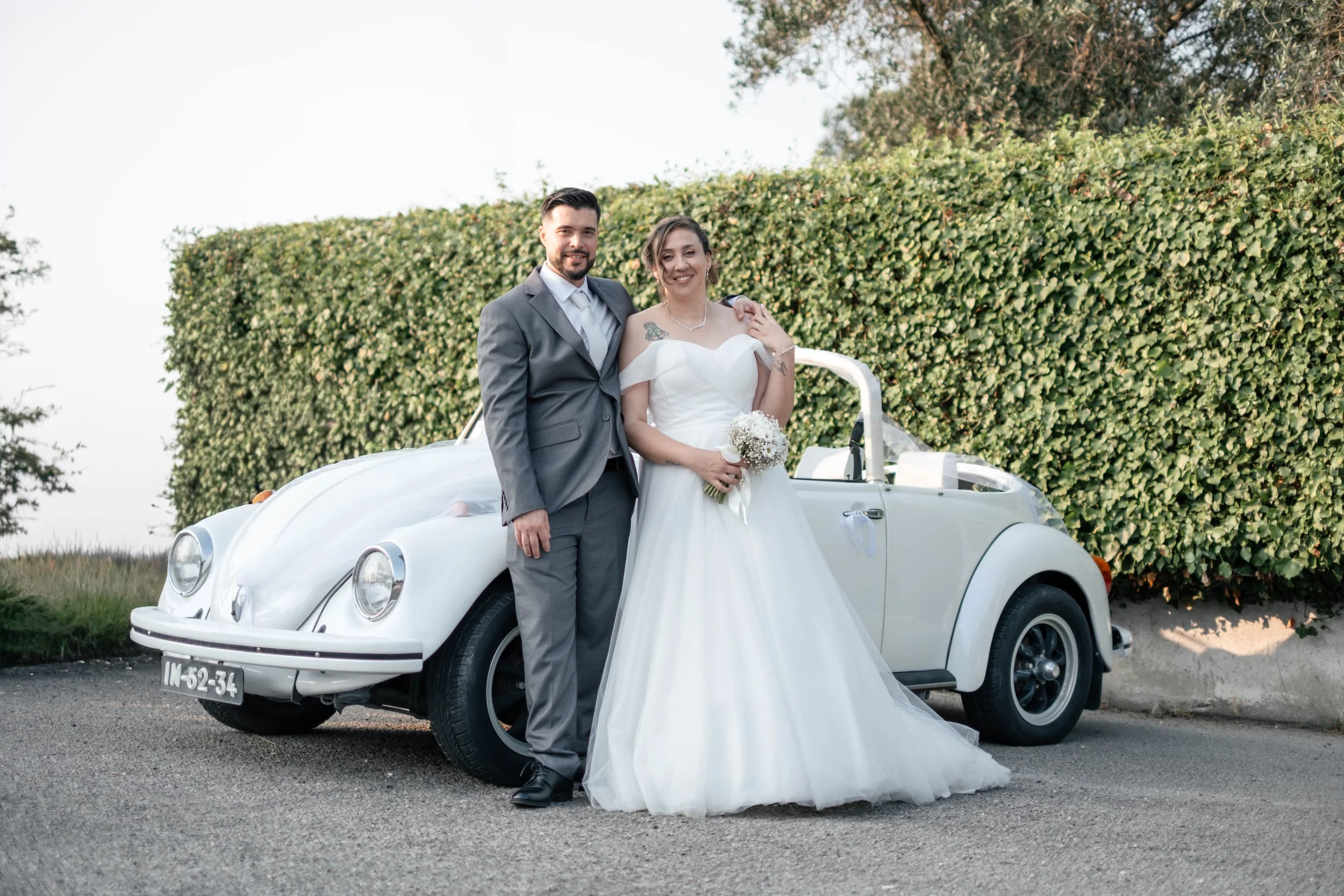 Noivos em retrato de casamento junto a carro clássico branco