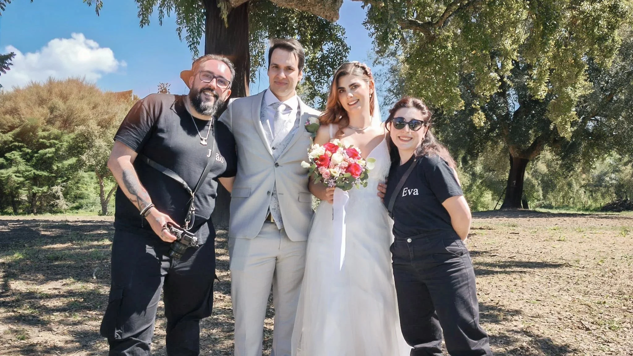 João e Eva com casal de noivos durante um casamento ao ar livre.