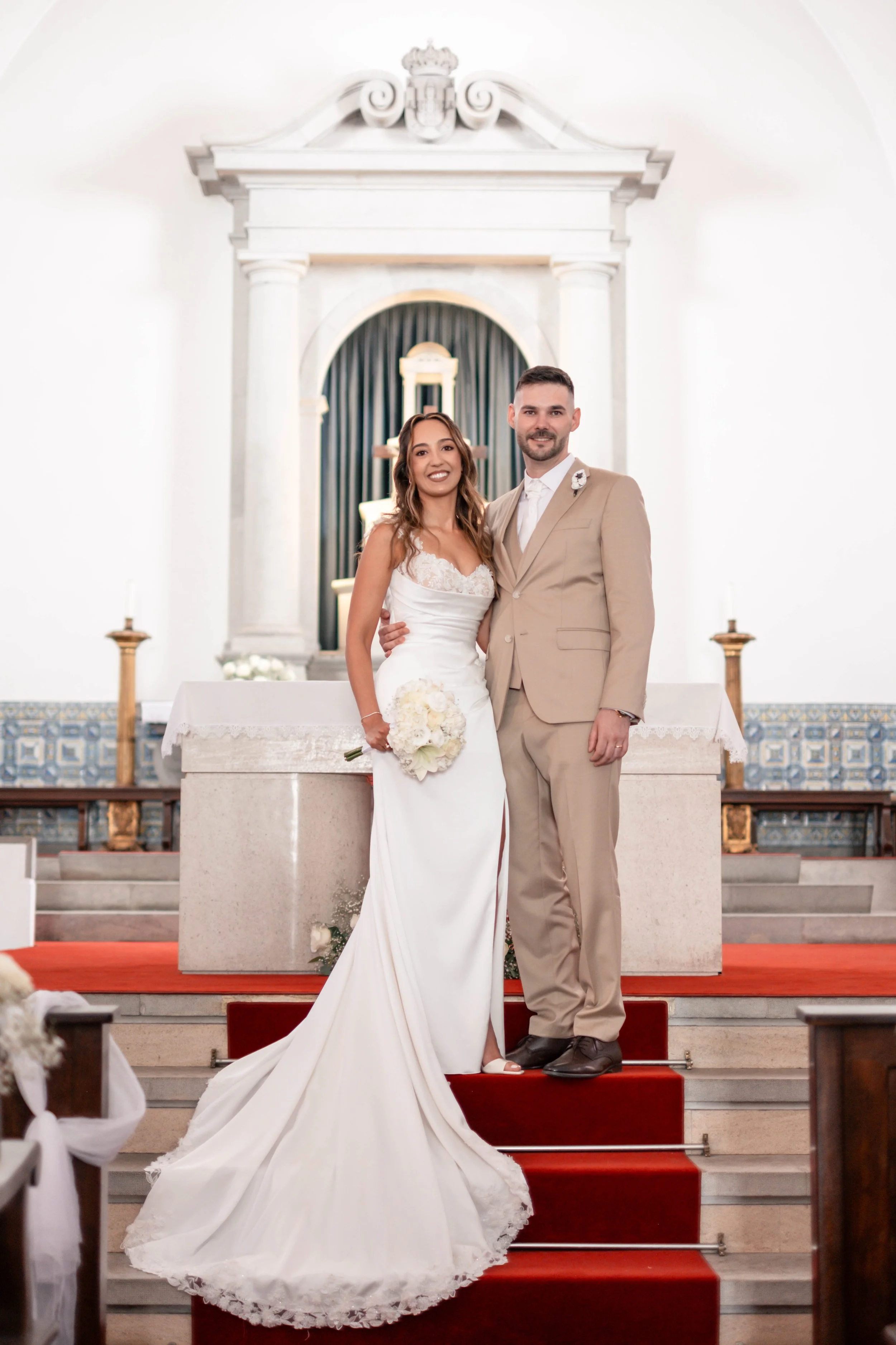 Noivos em retrato de corpo inteiro nas escadas do altar da igreja