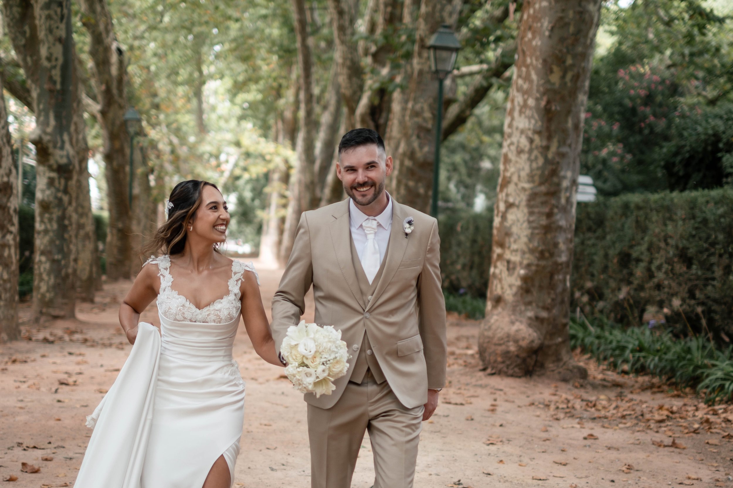 Noivos a rir de mãos dadas num jardim durante o casamento