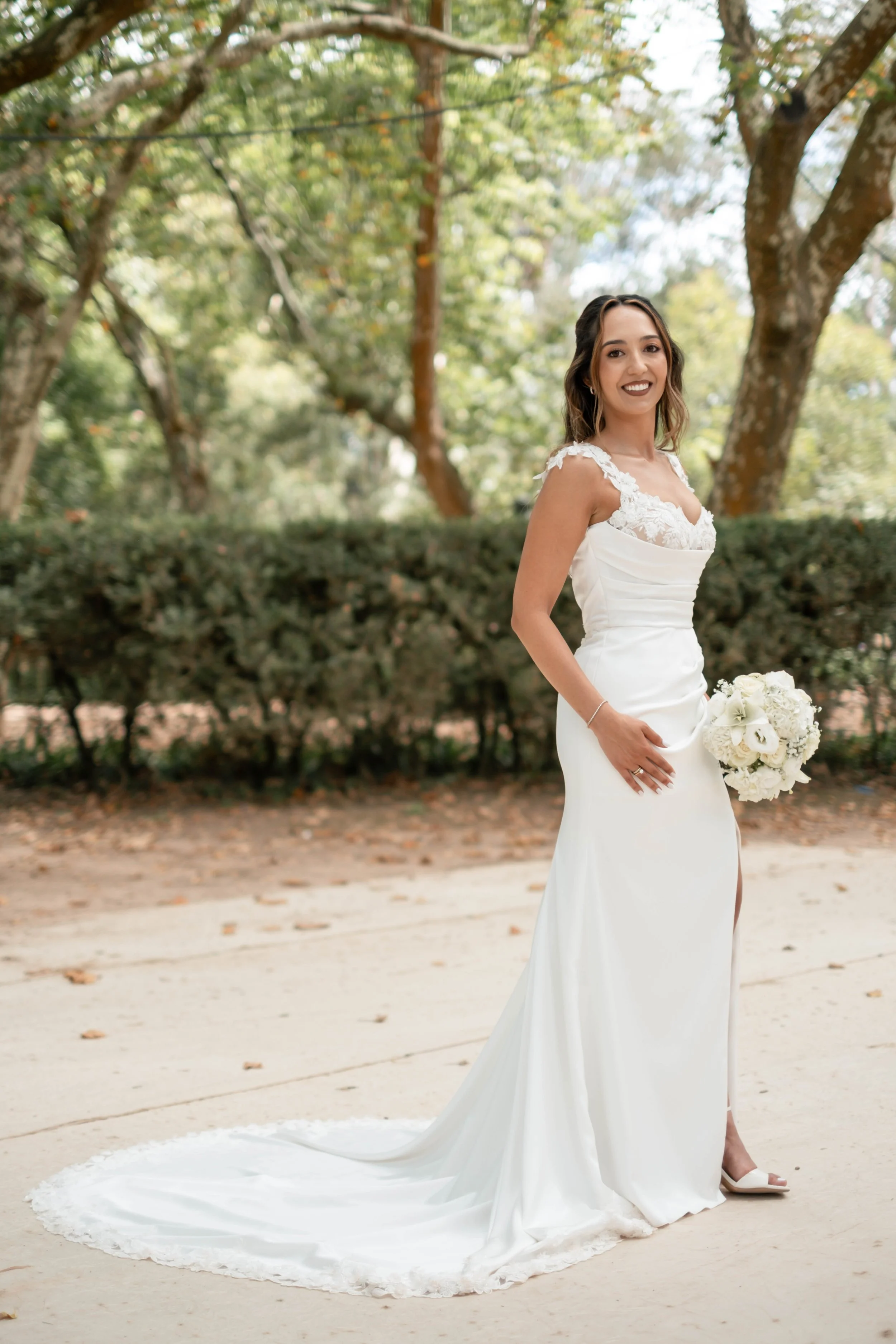 Noiva em pose elegante com vestido branco e cauda no jardim