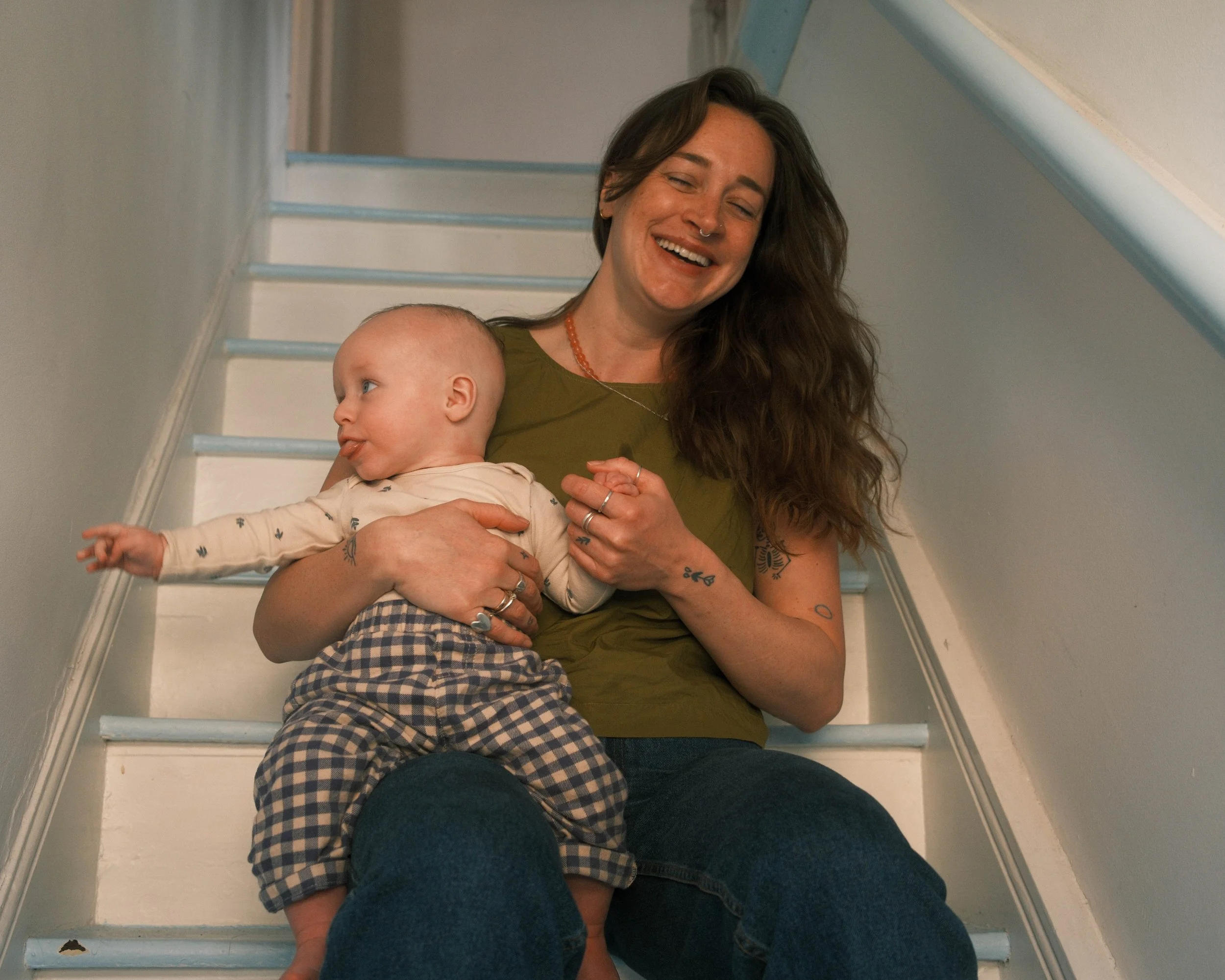 mother and son sitting on stairs and laughing, looking in different directions
