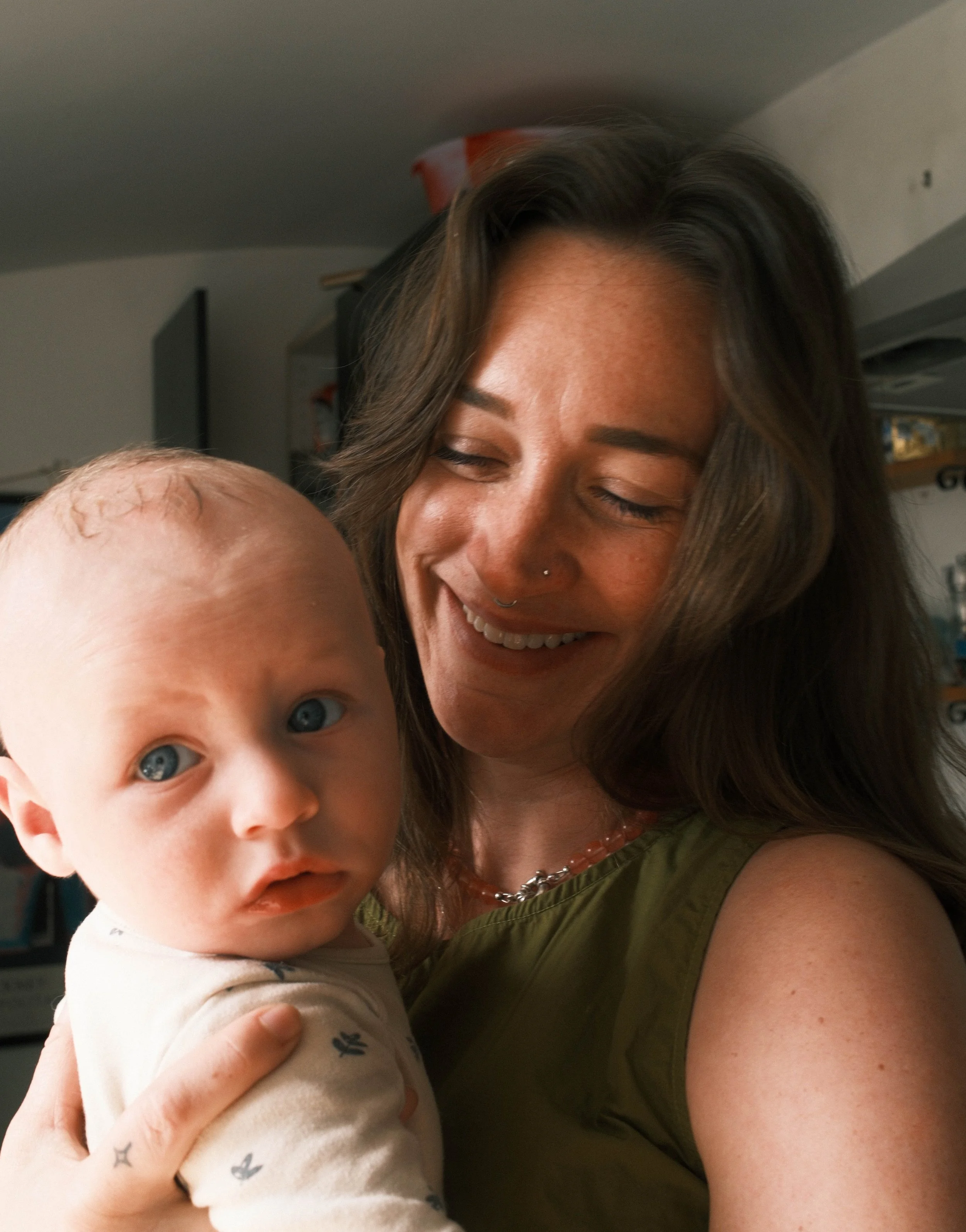 Mother smiling at her baby as she holds them.
