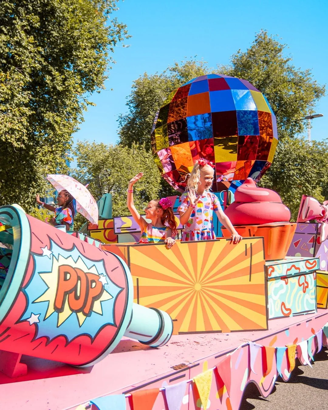 Children on top of a colourful carnival-style floatie with pop art decorations and a large mirrored disco ball sculpture at Moomba Festival 2026.