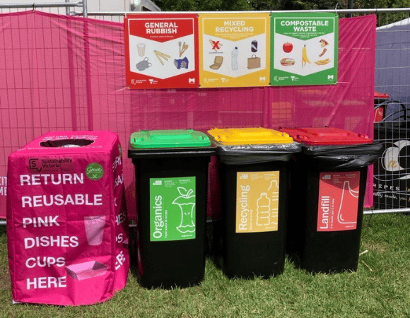 Pink branded reusable return bins beside organics, recycling, and landfill bins at Moomba Festival 2026.