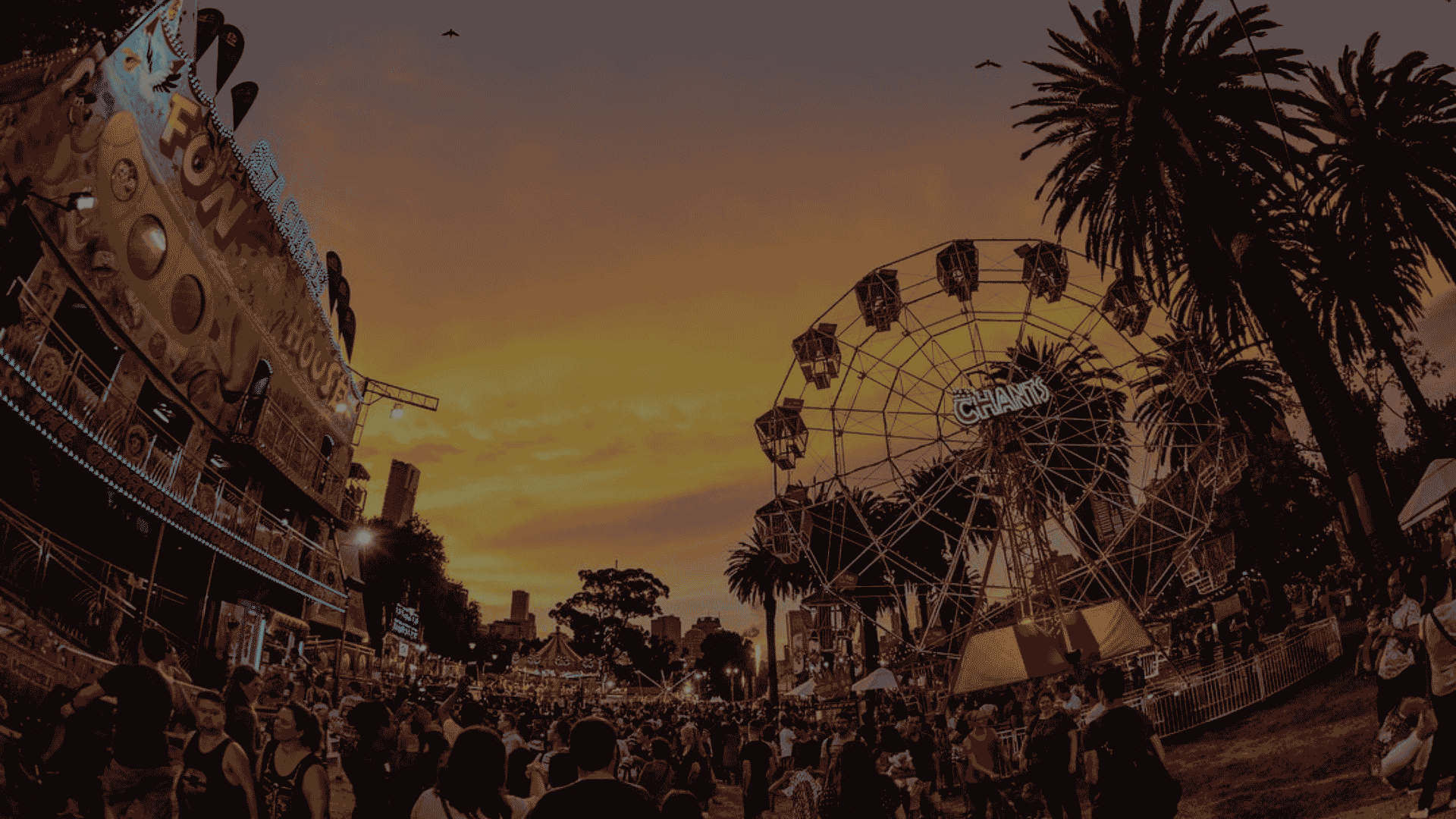 Crowd enjoying rides and attractions at Moomba Festival 2026 during sunset.