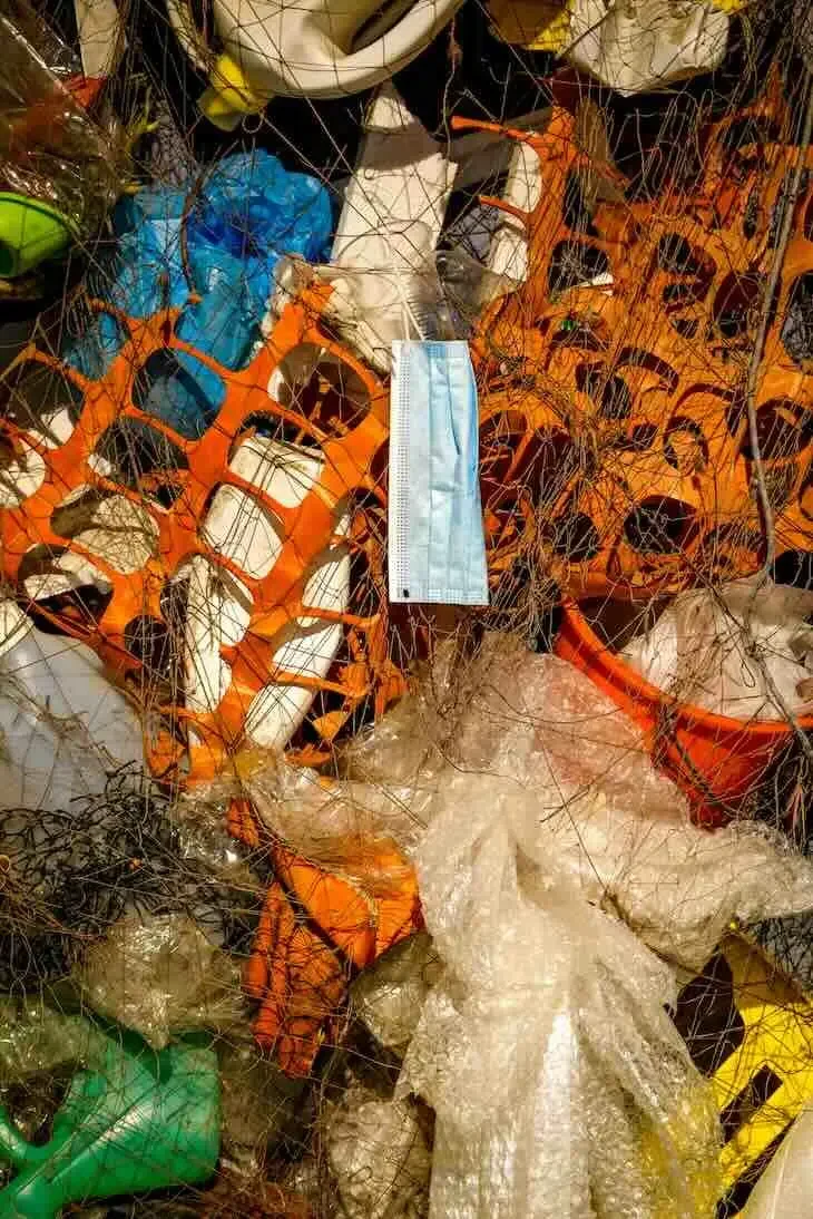 Pile of mixed garbage including plastic netting and face mask