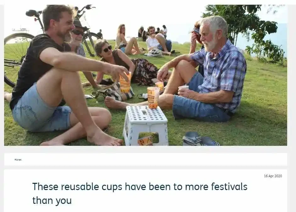 People drinking from Custom IML bettercup tumbler at an outdoor festival picnic setting.