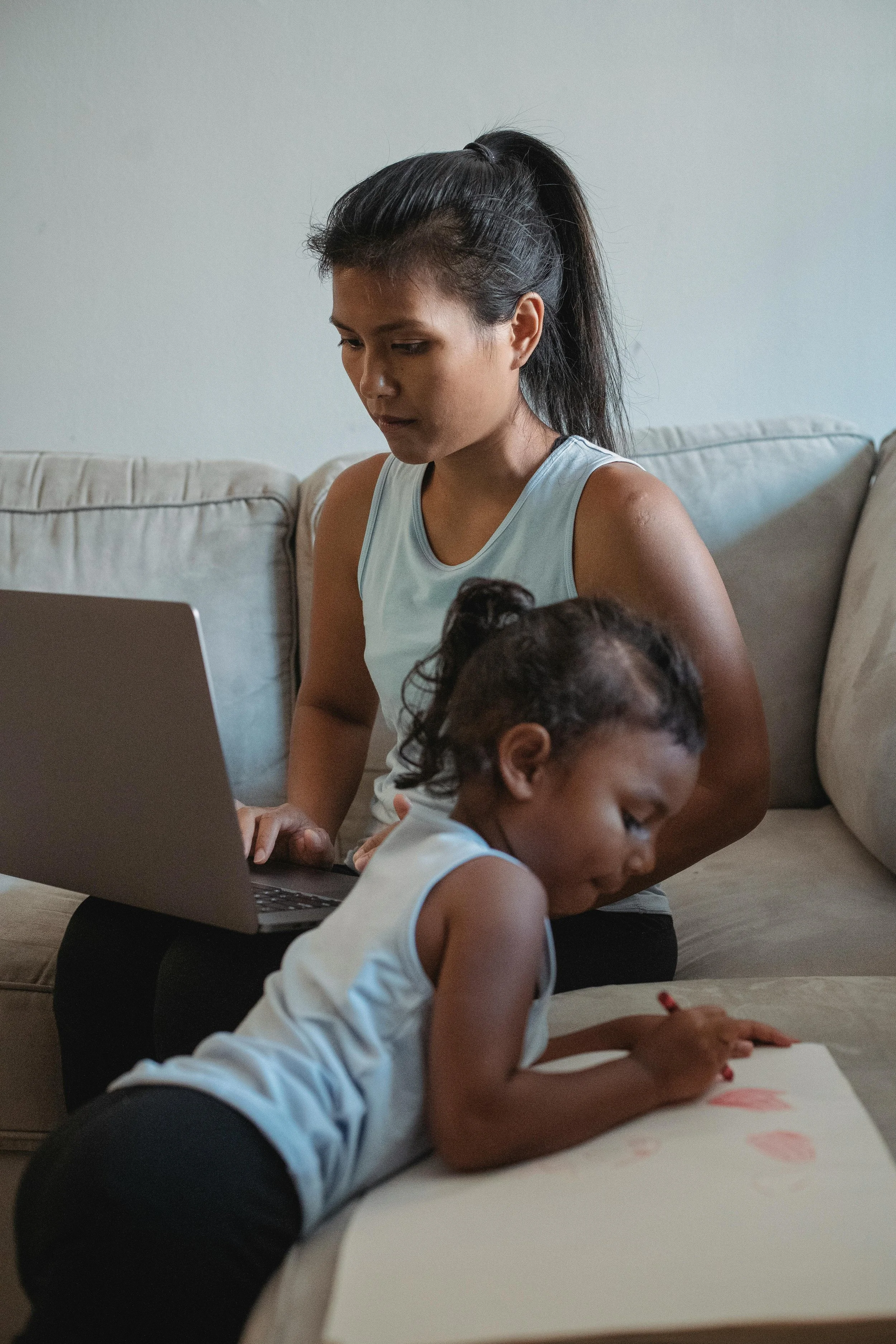 Stressed working mother sitting at her office desk feeling overwhelmed, representing the identity crisis and perfectionism of returning to work after maternity leave.