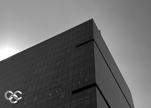 A modern glass skyscraper captured from a low angle, showing its reflective windows and sleek architecture.
