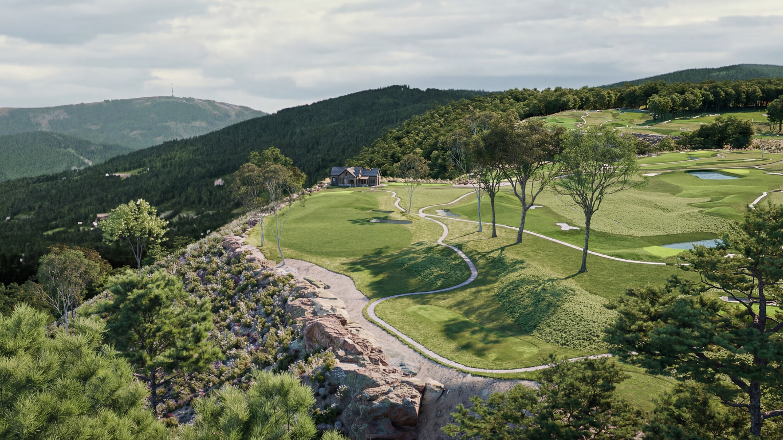 A scenic view of a golf course on a hillside with trees, water hazards, and a small house, set against distant mountains under a partly cloudy sky.
