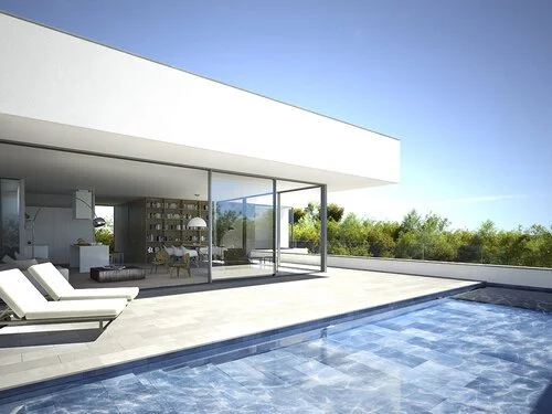 Modern house with an outdoor swimming pool and two lounge chairs on a sunny day.
