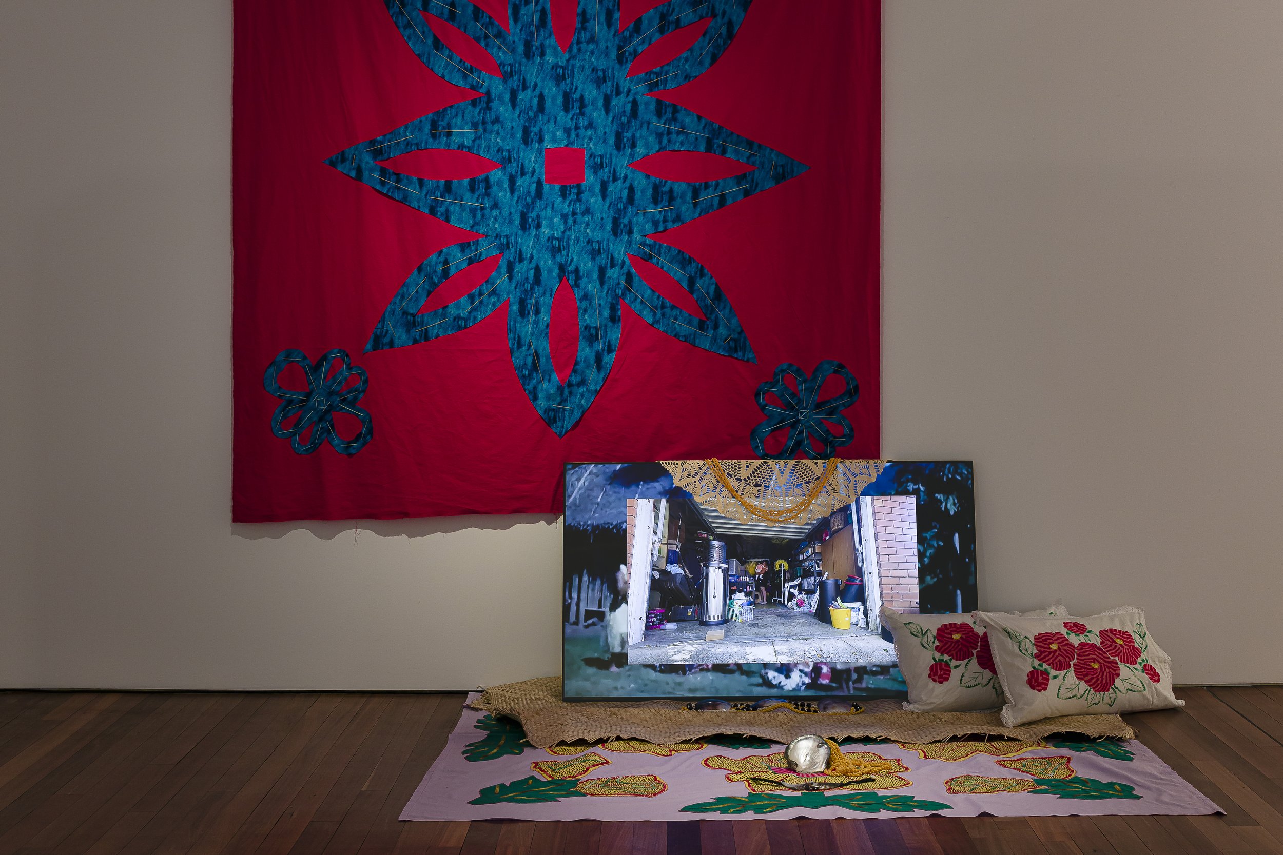 Morgan Hogg, Don't Cry My Moko, 2023, Embroidery on quilt fabric, tivaevae, woven mat, Pupu shell necklaces, crochet doily, pearl shells, pearl shell necklace, tivaevae pillows and gardenia oil. Single screen video, 04:13 mins. , Fauvette Loureiro Me