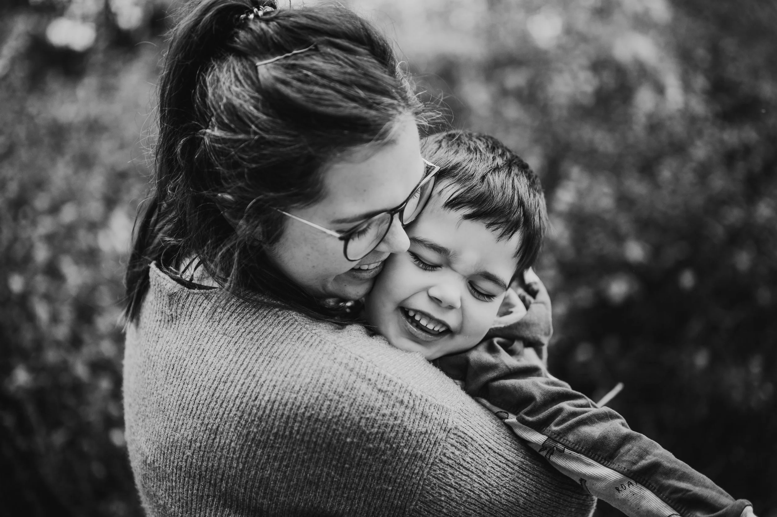 Emotionale Schwarzweiß-Aufnahme einer Mama, die ihr Kind fest umarmt – natürliche, ungestellte Familienfotos in Brandenburg & Sachsen (Reportage-Stil). 