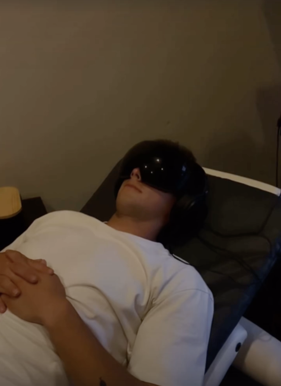 Man laying on PEMF mat with light therapy goggles on