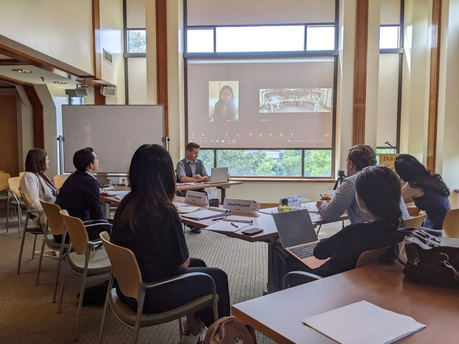 Workshop participants around the conference table at Duke, with remote participants on screen