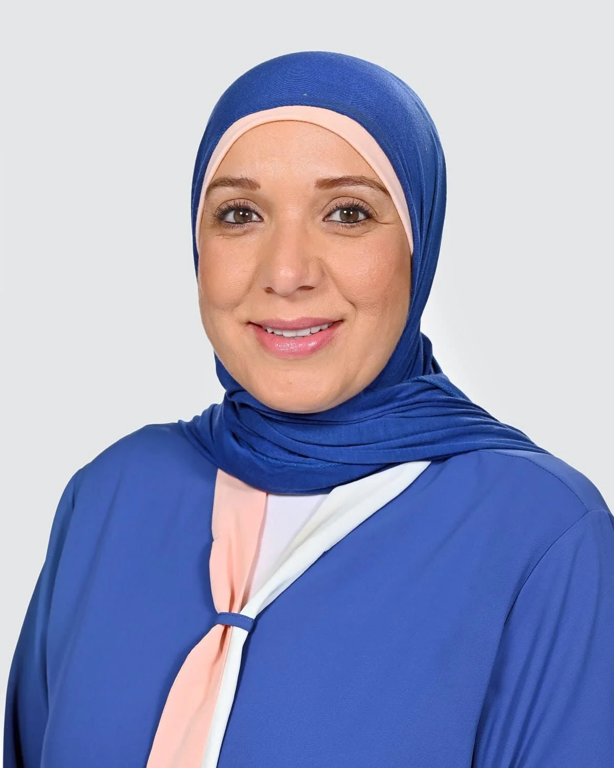 Dr Ibtihaje El Senne, smiling, wearing a blue and light pink hijab and matching garment.