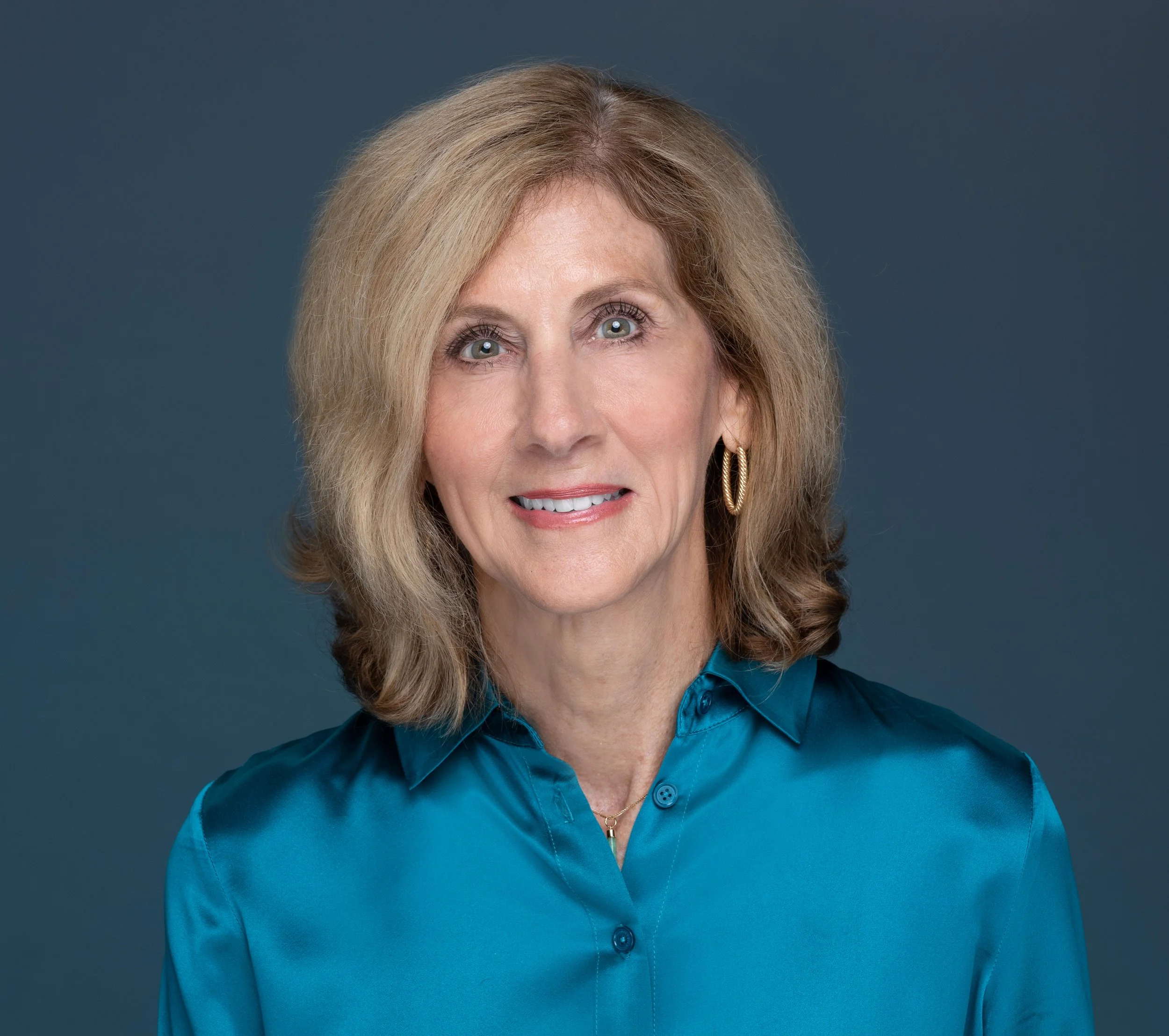 Pictured in a teal silk blouse, Vicki Denmark's friendly smile lights up her eyes