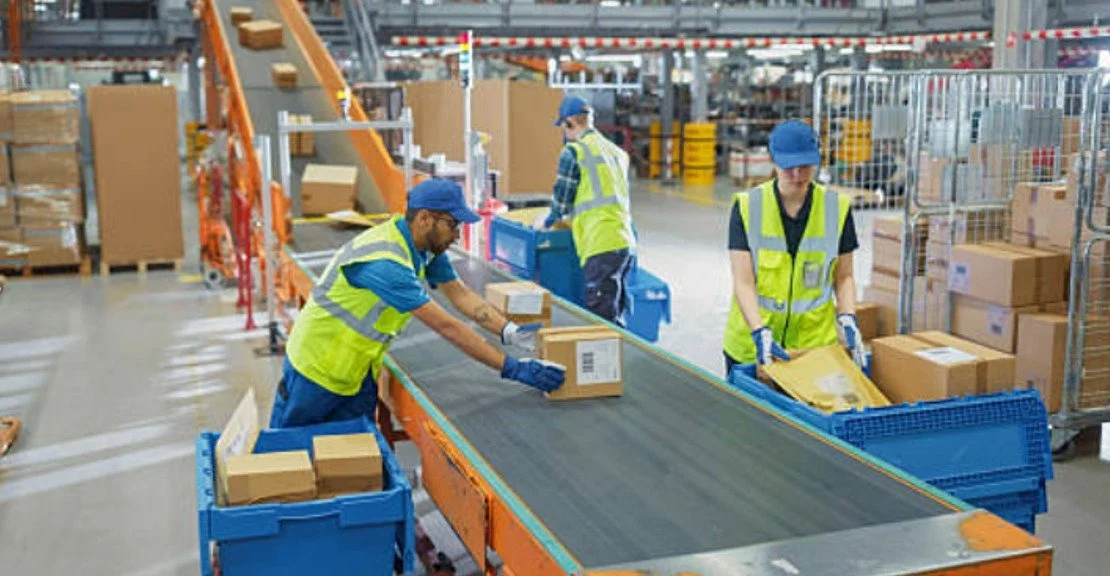 a group of workers handling boxes on a conveyor. Routed Delivery Service