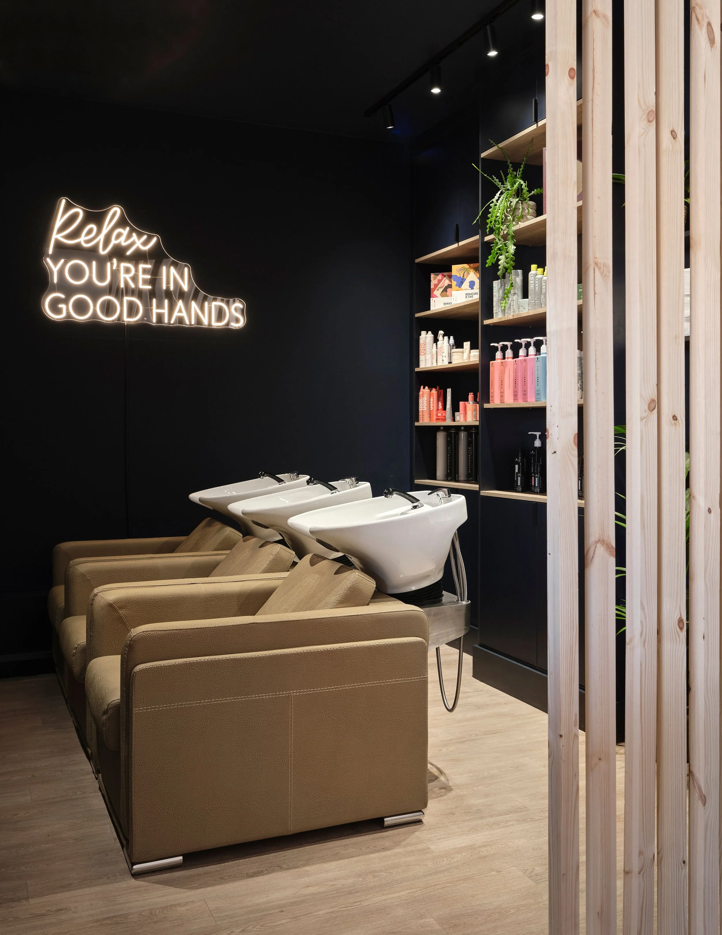 Dark cocooning walls and ceiling in the calm washing area of 5th Avenue Salon in Bedford