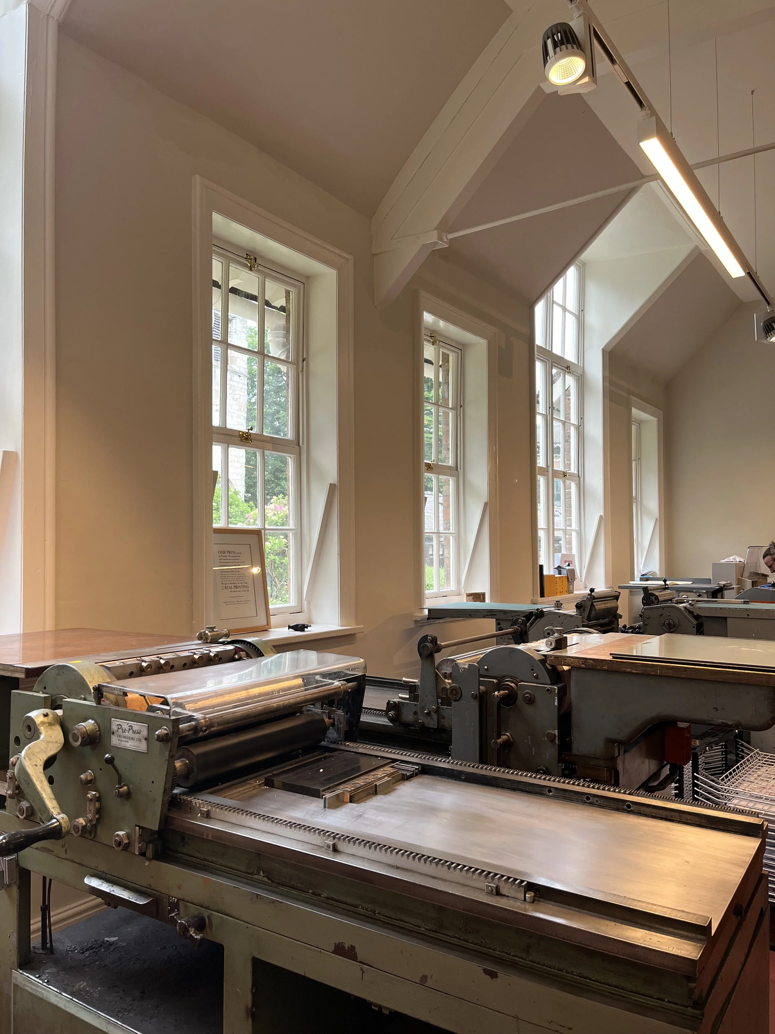 A 1960s printing press machine in a room with tall windows and natural light.
