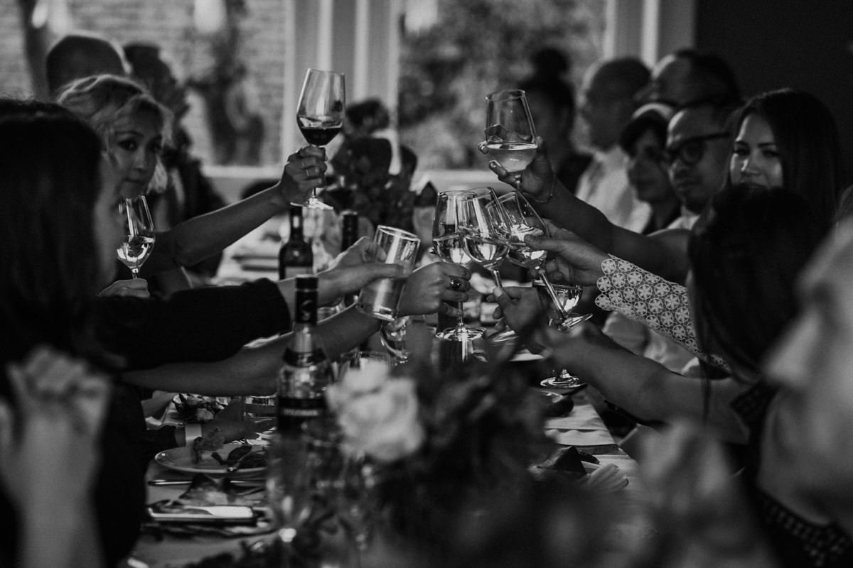Group of people at a party making a toast with wine glasses.