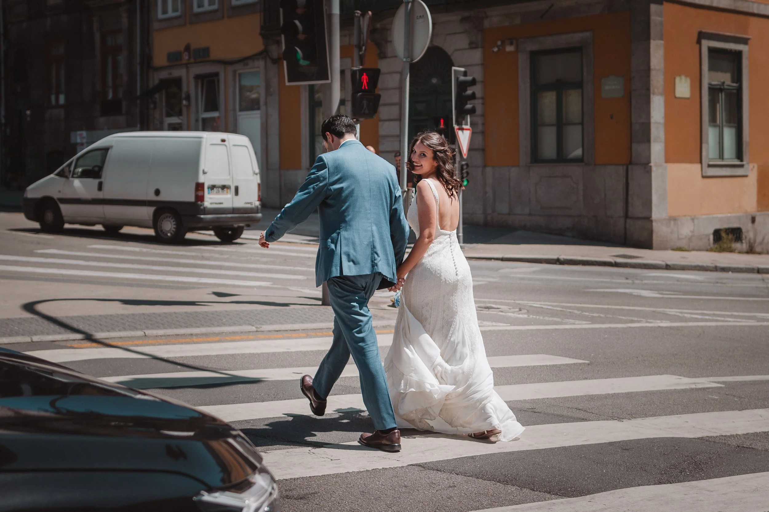 Casal de noivos caminhando na faixa de pedestres em uma rua urbana