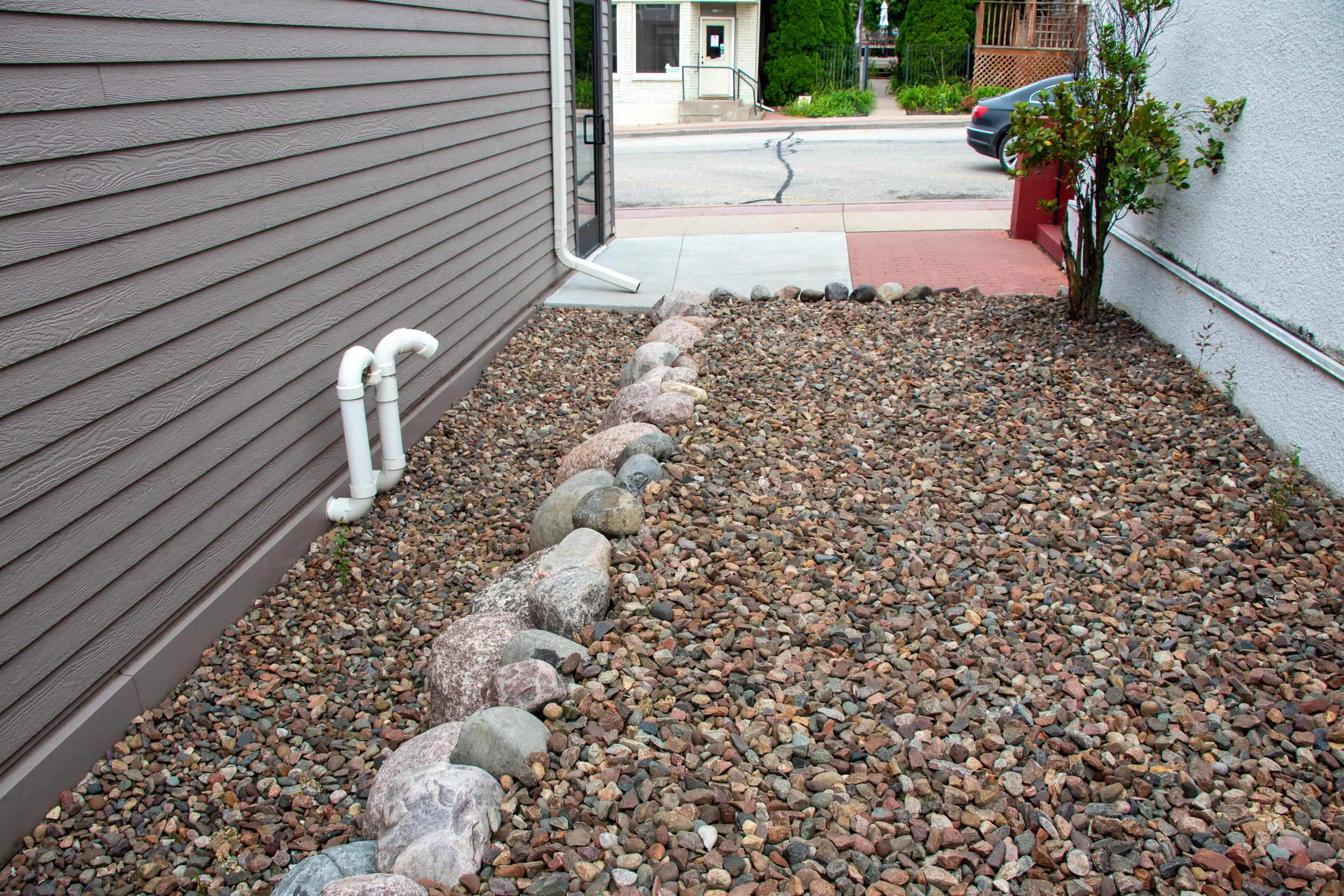 Decorative stone bed with natural boulder border along structure.