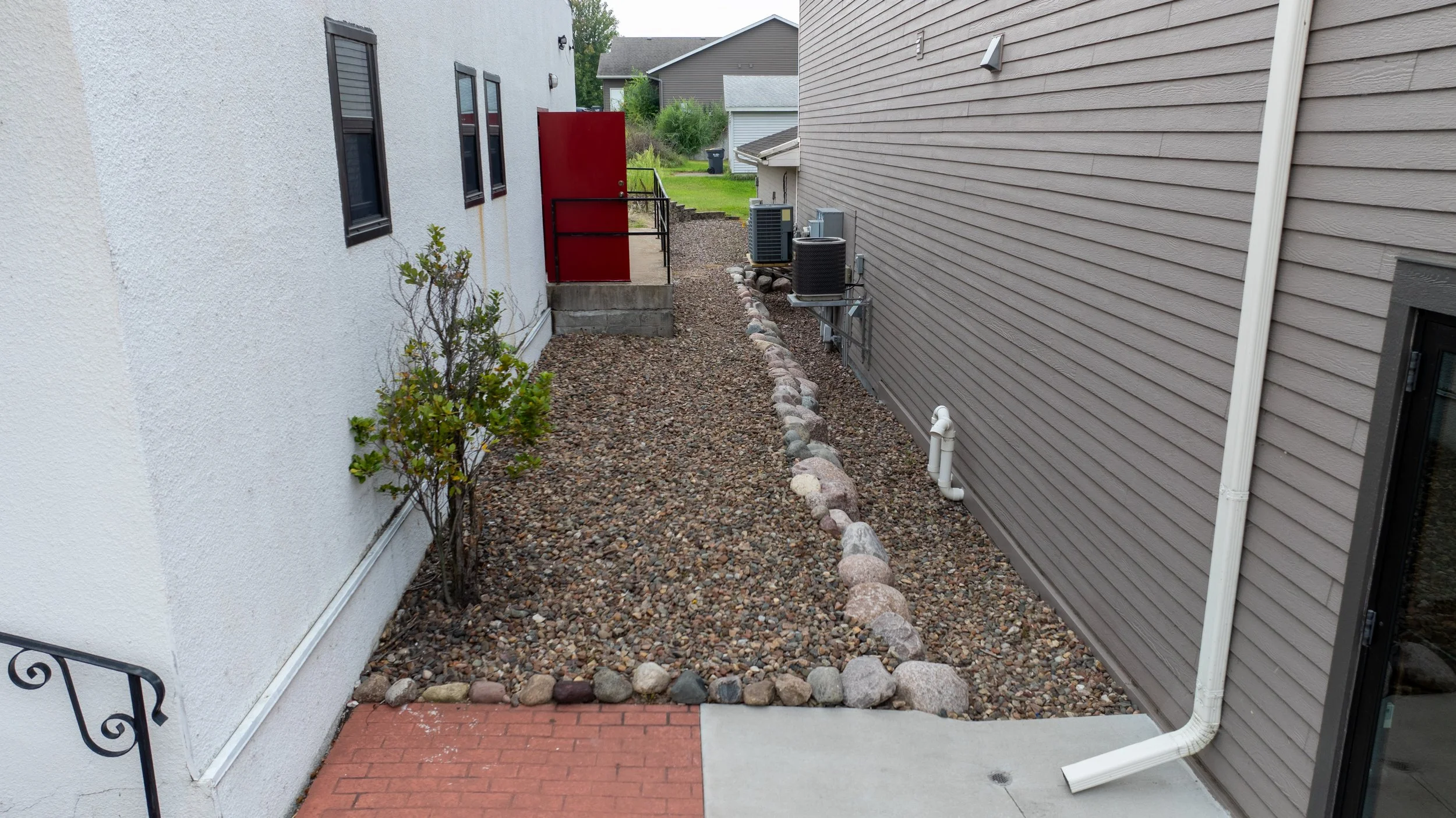 Side yard with stone ground cover and boulder retaining edge.