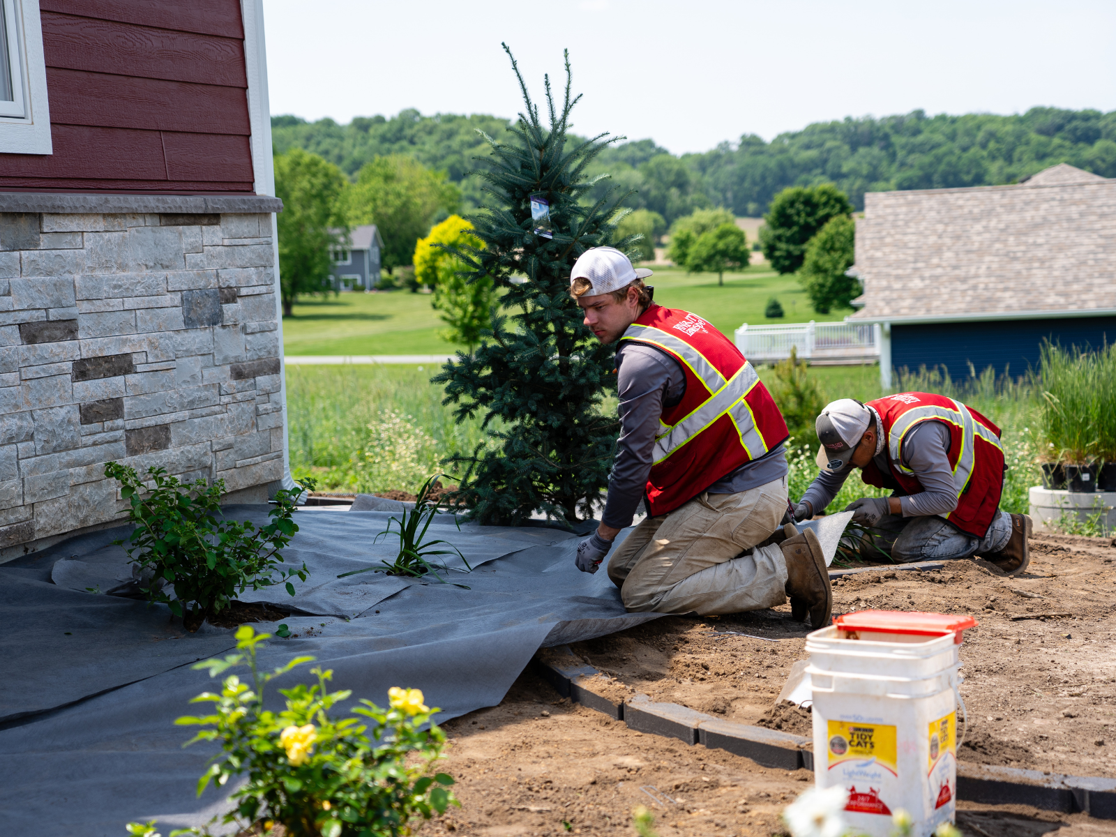  Landscape installation crew installing landscape fabric and base material near patio area 