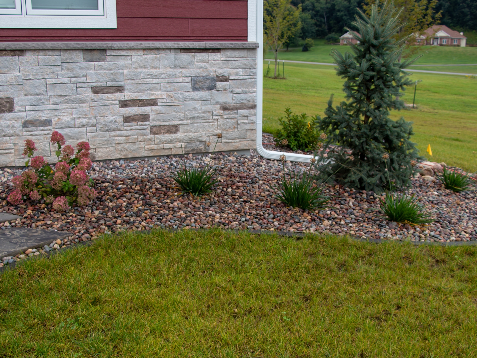  Landscape planting bed with stone edging and newly installed shrubs along home exterior 