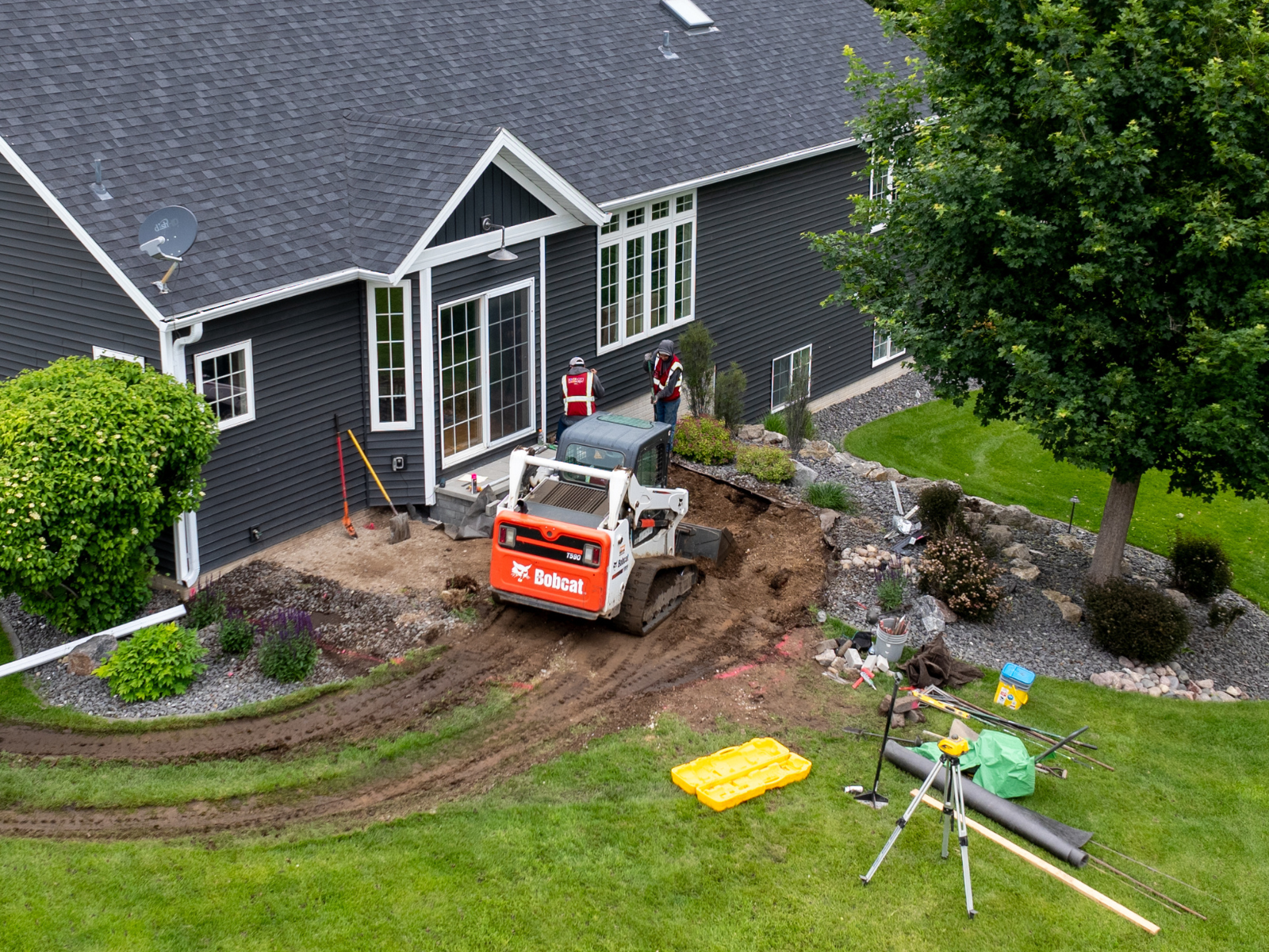 Aerial view of active patio installation with equipment positioned near the home.