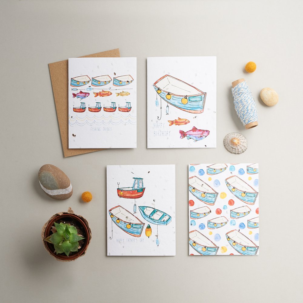  Four greeting cards in nautical design photographed with nautical props on rustic planked surface 