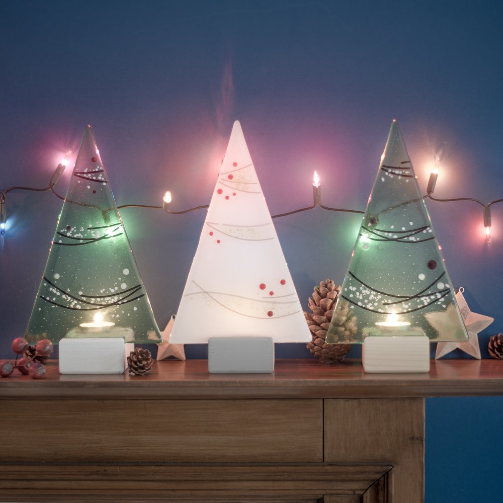  Decorative glass Christmas trees on top of fireplace with dark blue background 